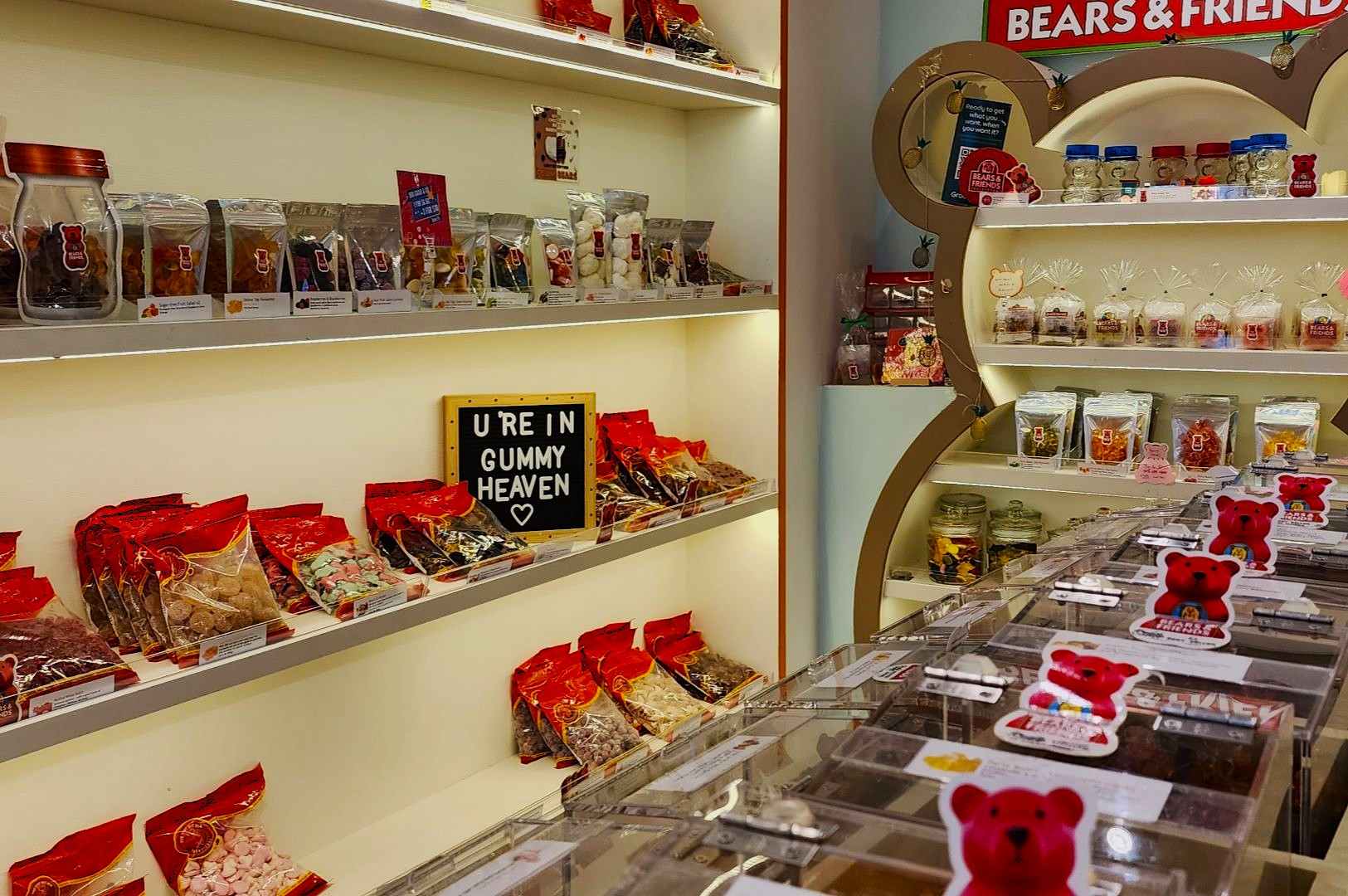 A bright candy store with shelves of colorful gummy packages and jars, a sign stating "U R in Gummy Heaven" conveys a playful, inviting atmosphere.