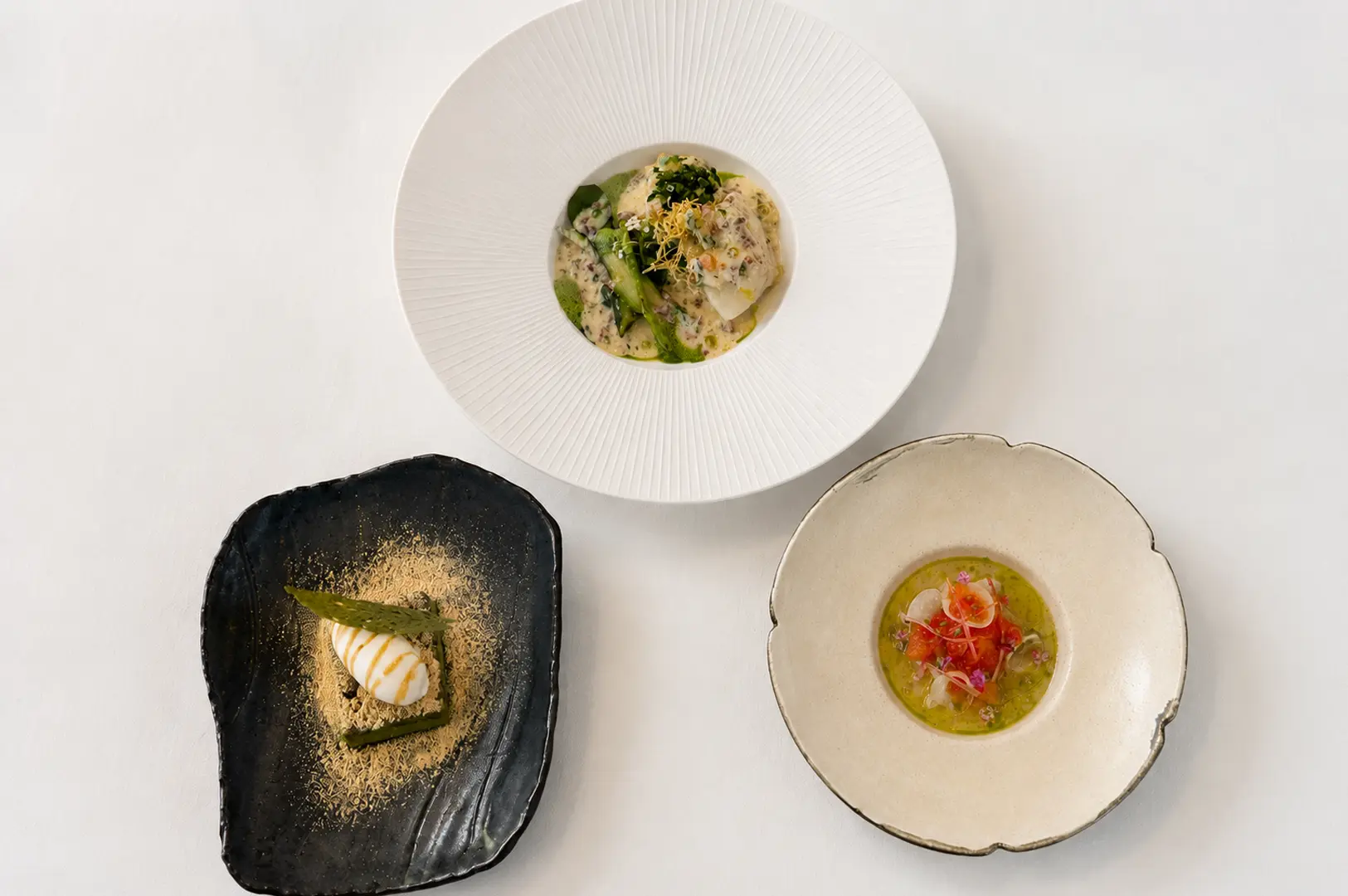 Elegant plated fish dish with yellow sauce and delicate flower garnish on a white table