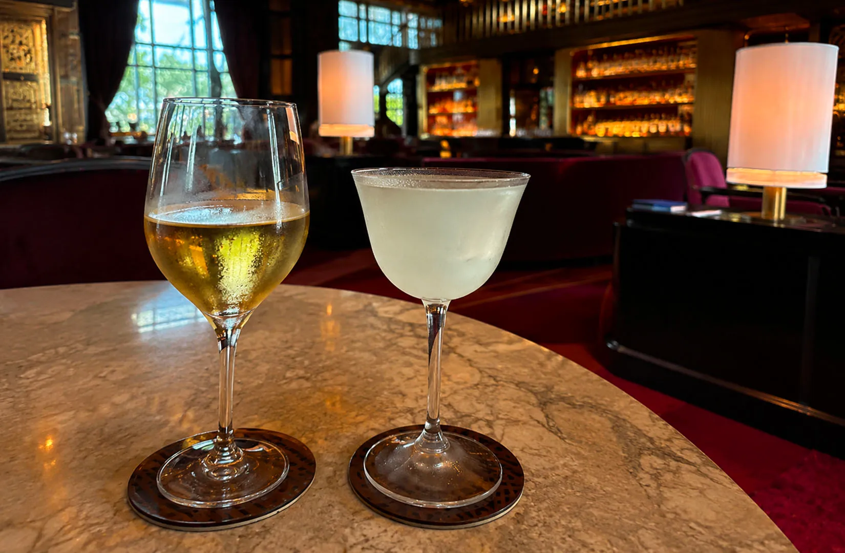 Two cocktails on a dimly lit table with a small lamp.