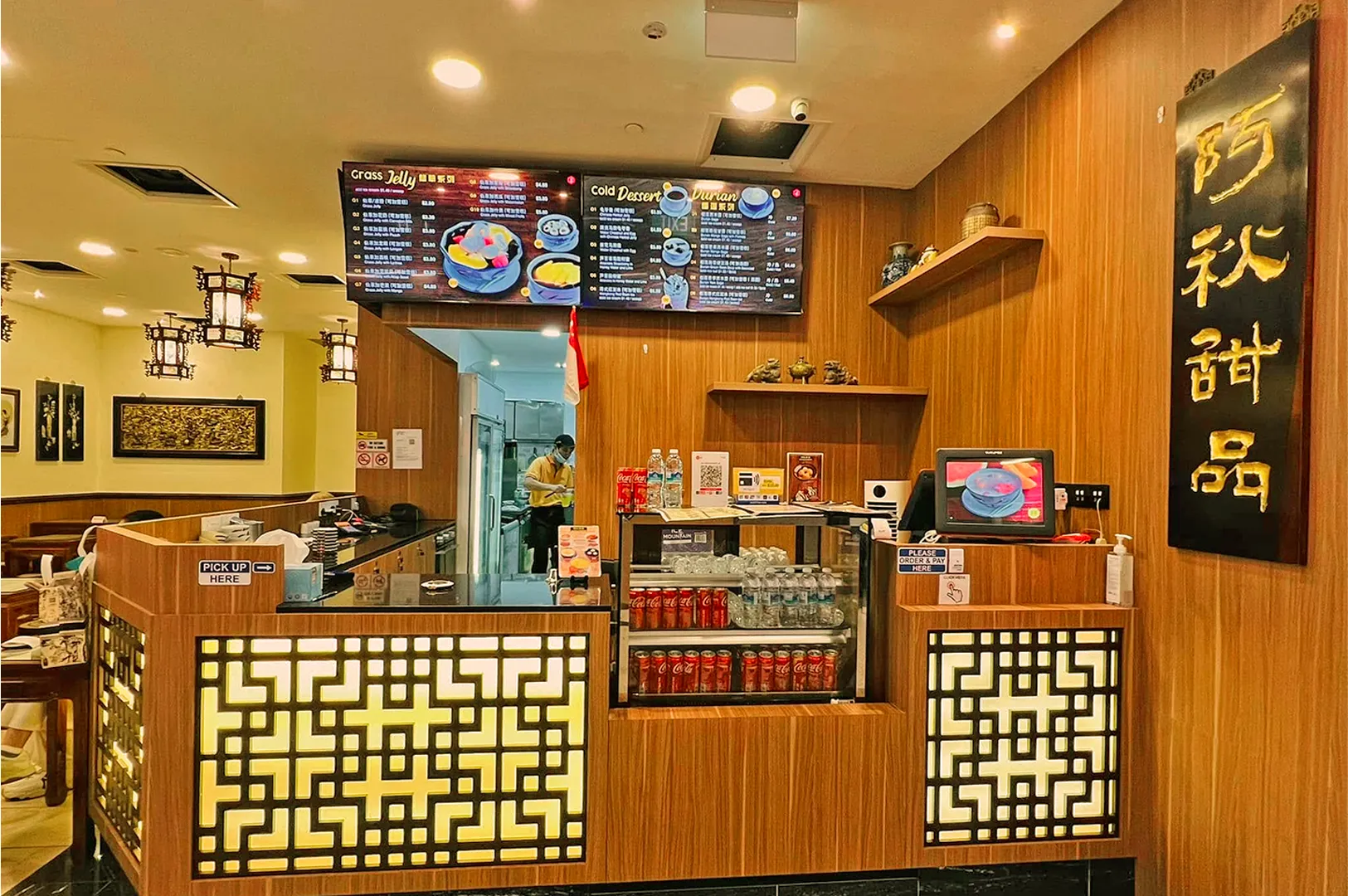 Cozy dessert shop interior with a wooden counter, illuminated lattice design, menu board, and traditional decor. Warm ambiance and inviting atmosphere.