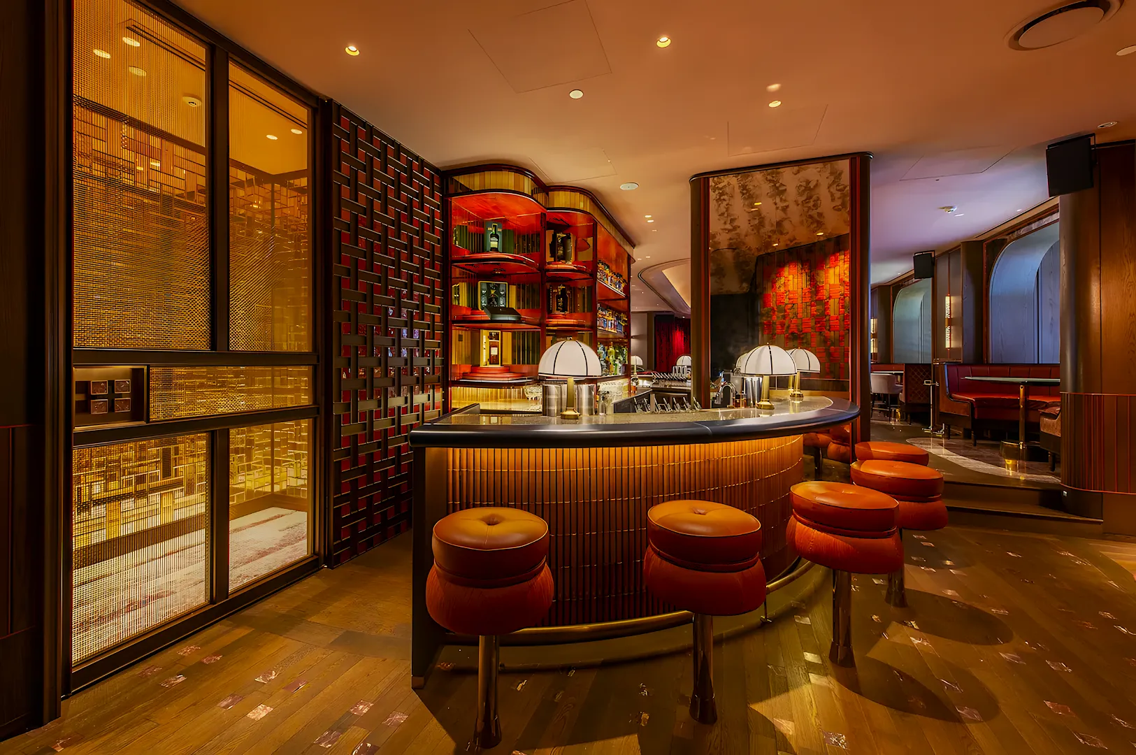 Chic bar interior with warm lighting, featuring a curved counter, modern stools, and backlit shelving. The atmosphere is elegant and inviting.
