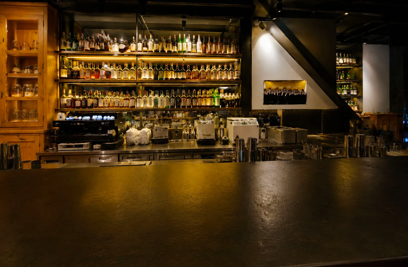 A warmly lit bar interior with shelves full of liquor bottles.