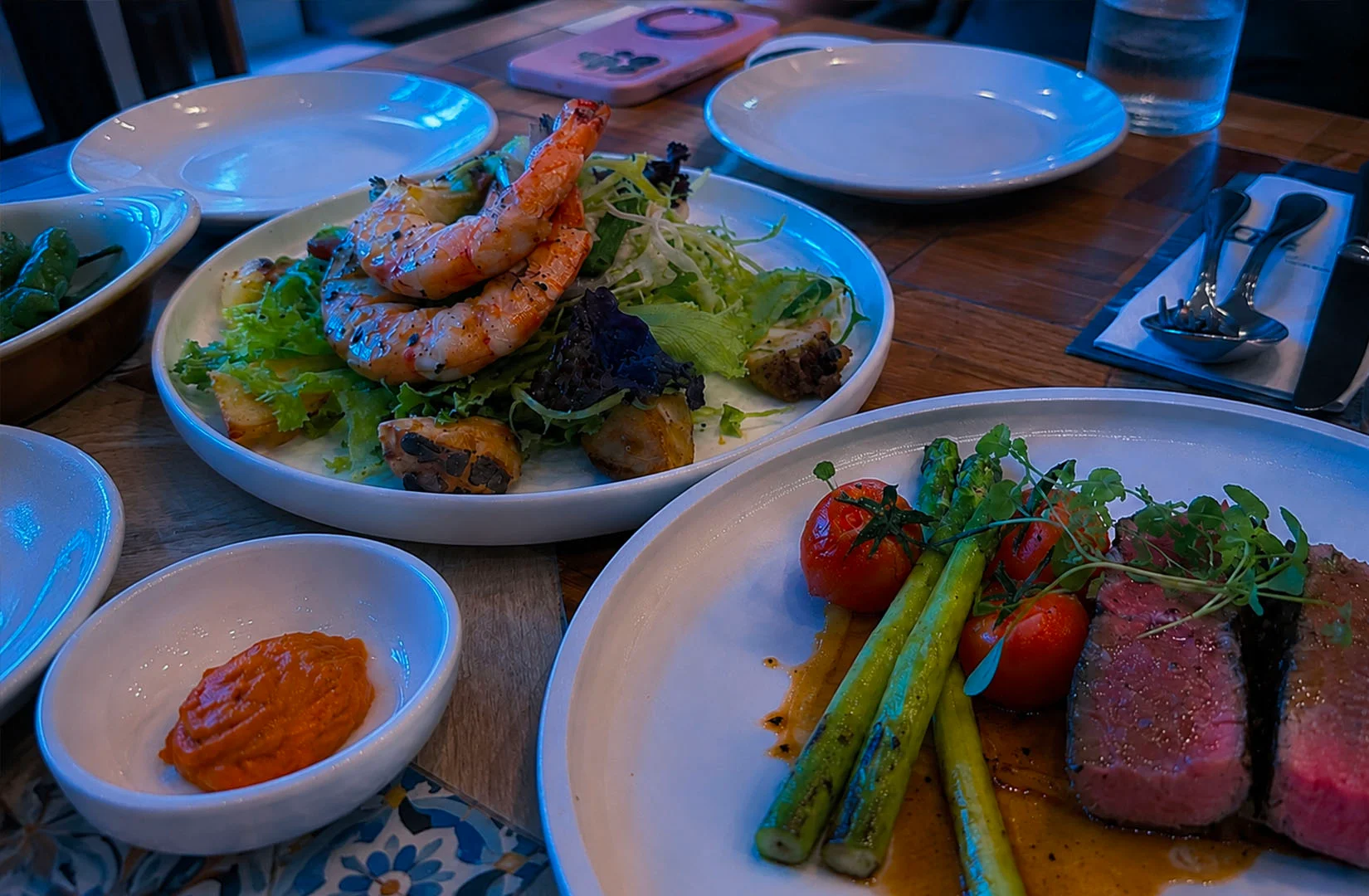 Restaurant meal with steak, shrimp salad, and blue lighting