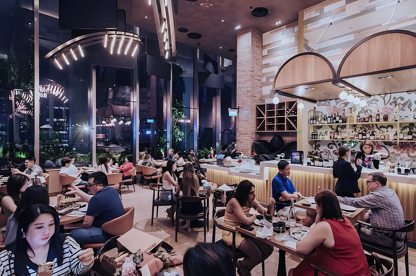 A lively restaurant scene with people dining at tables, a modern bar in the background, and warm lighting creating a cozy, vibrant atmosphere.