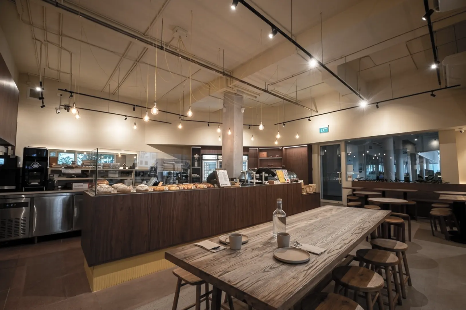 Modern café interior with wooden counter, communal table, and pendant lighting
