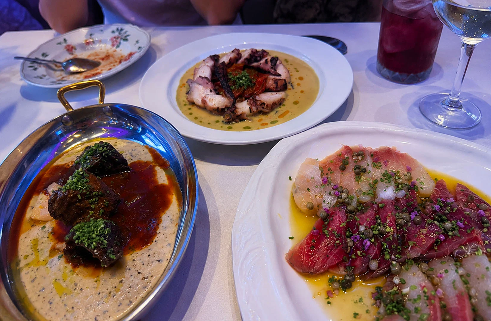 Fine dining table with plated dishes and colorful drinks