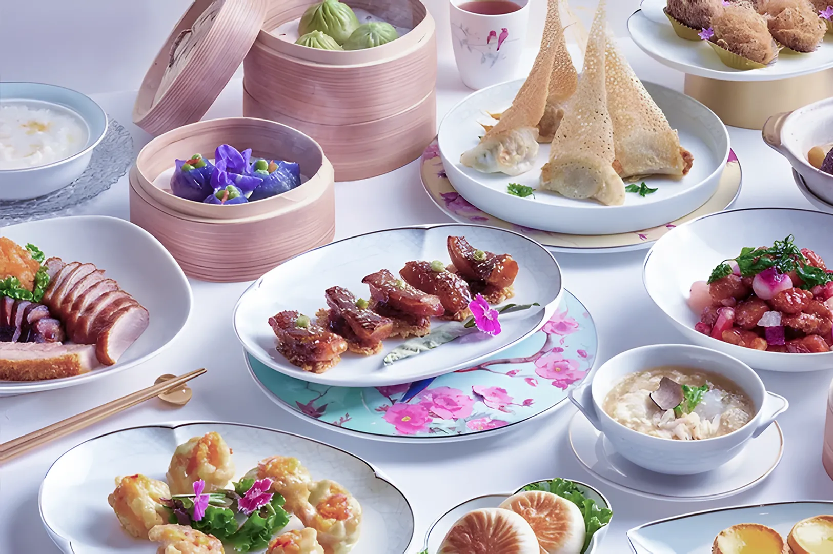 A variety of elegant dim sum dishes on a white table. Includes dumplings in bamboo steamers, roast duck, and decorative plates with vibrant floral accents.