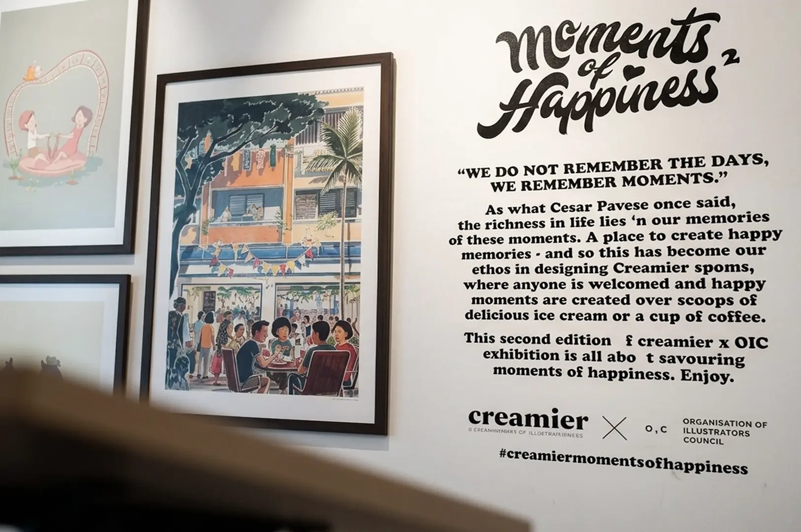 Wall display featuring "Moments of Happiness" quote and framed illustrations for a Creamier exhibition