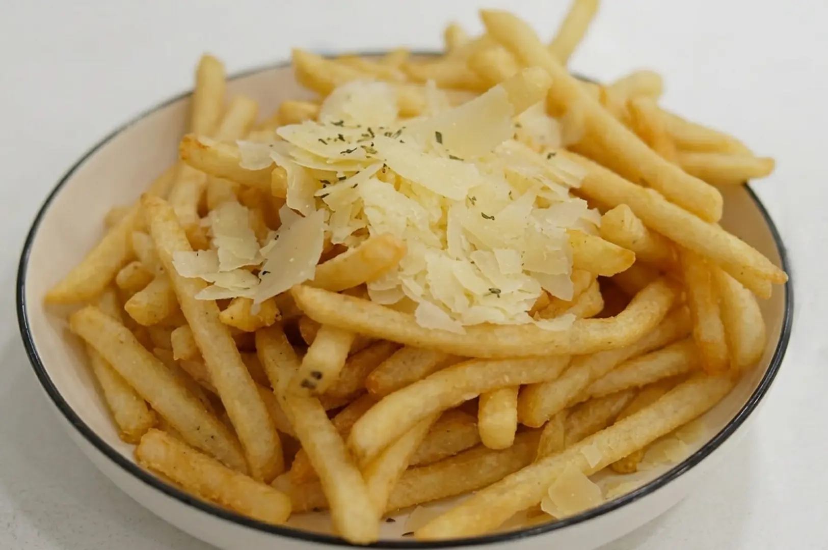 Golden french fries topped with shaved parmesan cheese and herbs