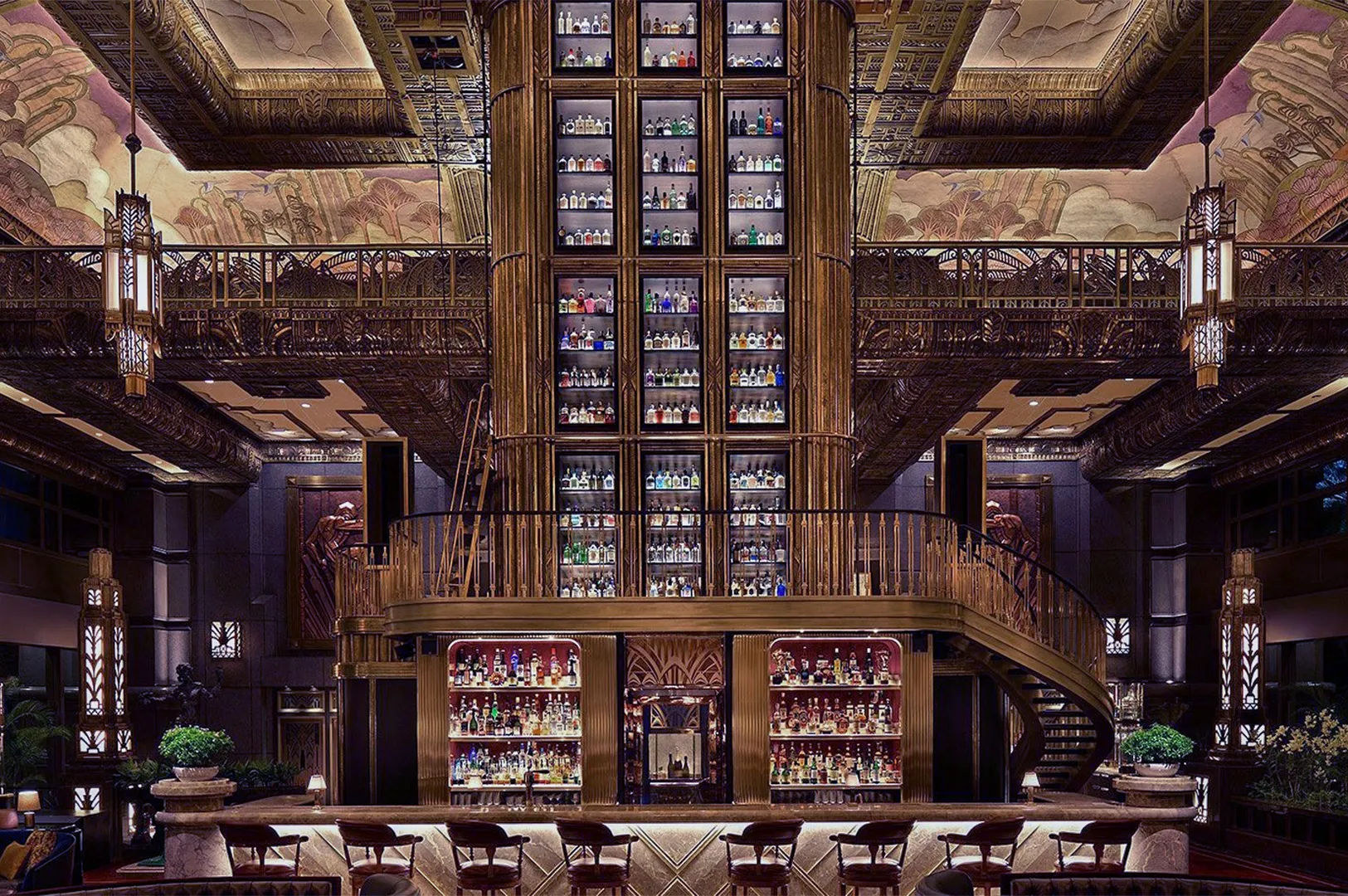 Luxurious bar with a towering liquor shelf, elegant spiral staircase, and art deco design. Warm lighting creates a sophisticated atmosphere.