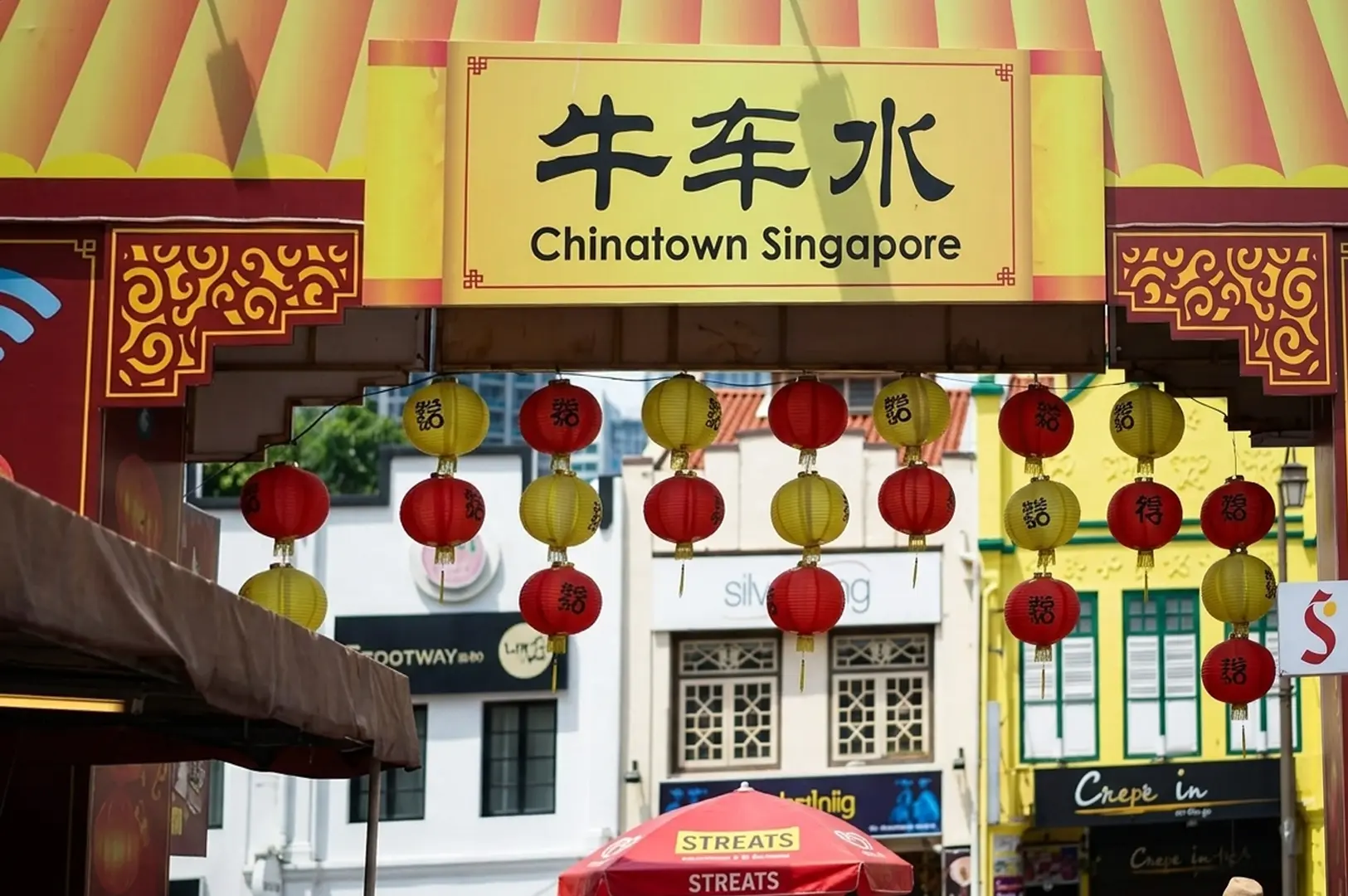 Chinatown Singapore entrance with red and yellow lanterns hanging above market street