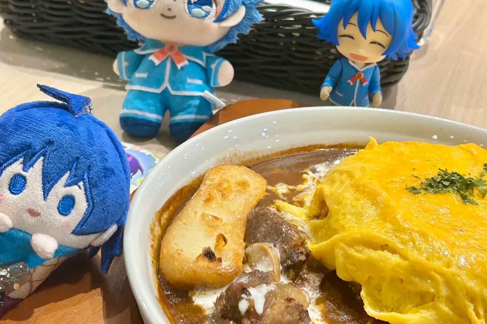 Plate of omurice with demi-glace sauce, toast, and mushrooms served at Hoshino Coffee, accompanied by blue-haired plush toys