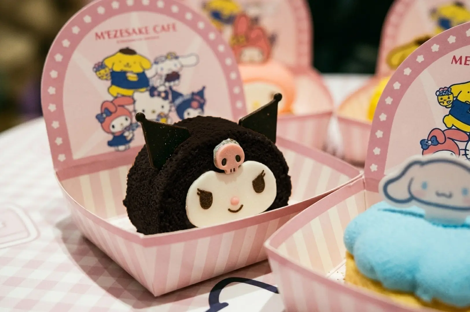 Kuromi and Cinnamoroll character desserts in pink striped boxes at Mezesake Cafe with Sanrio character branding