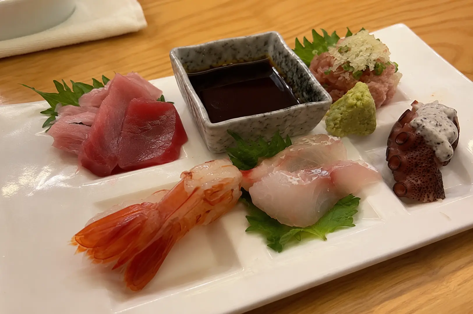 Fresh sashimi platter with tuna, sweet shrimp, white fish, octopus, and minced tuna served with soy sauce and wasabi.