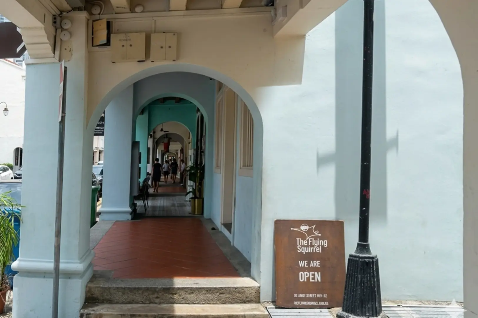 Arched walkway entrance leading to The Flying Squirrel with an open signboard displayed outside