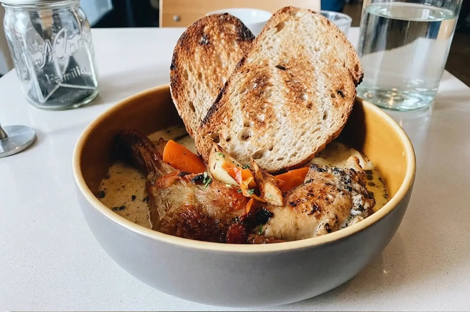 Hearty chicken stew with carrots and toasted bread slices served in a yellow-rimmed bowl
