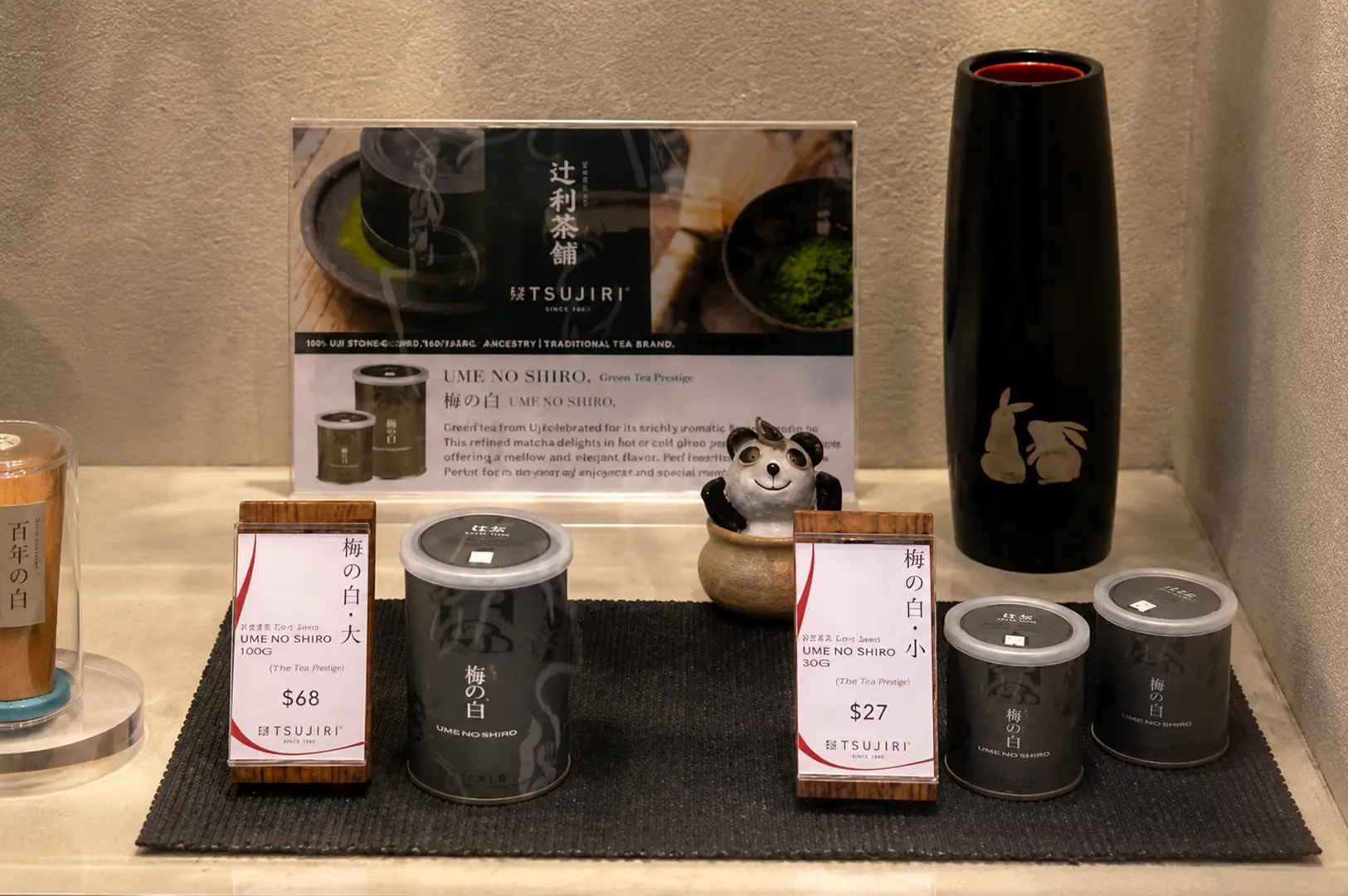 Display of Ume No Shiro premium matcha tea tins with price tags and traditional Japanese tea accessories