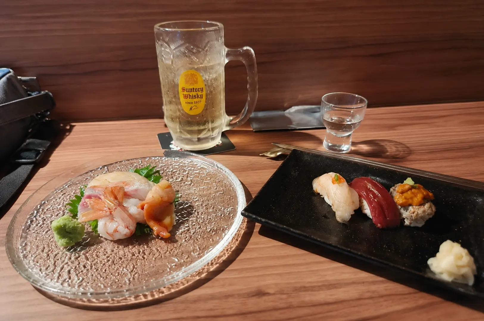 Sushi and sashimi set served with a Suntory Whisky highball at a modern Japanese restaurant.