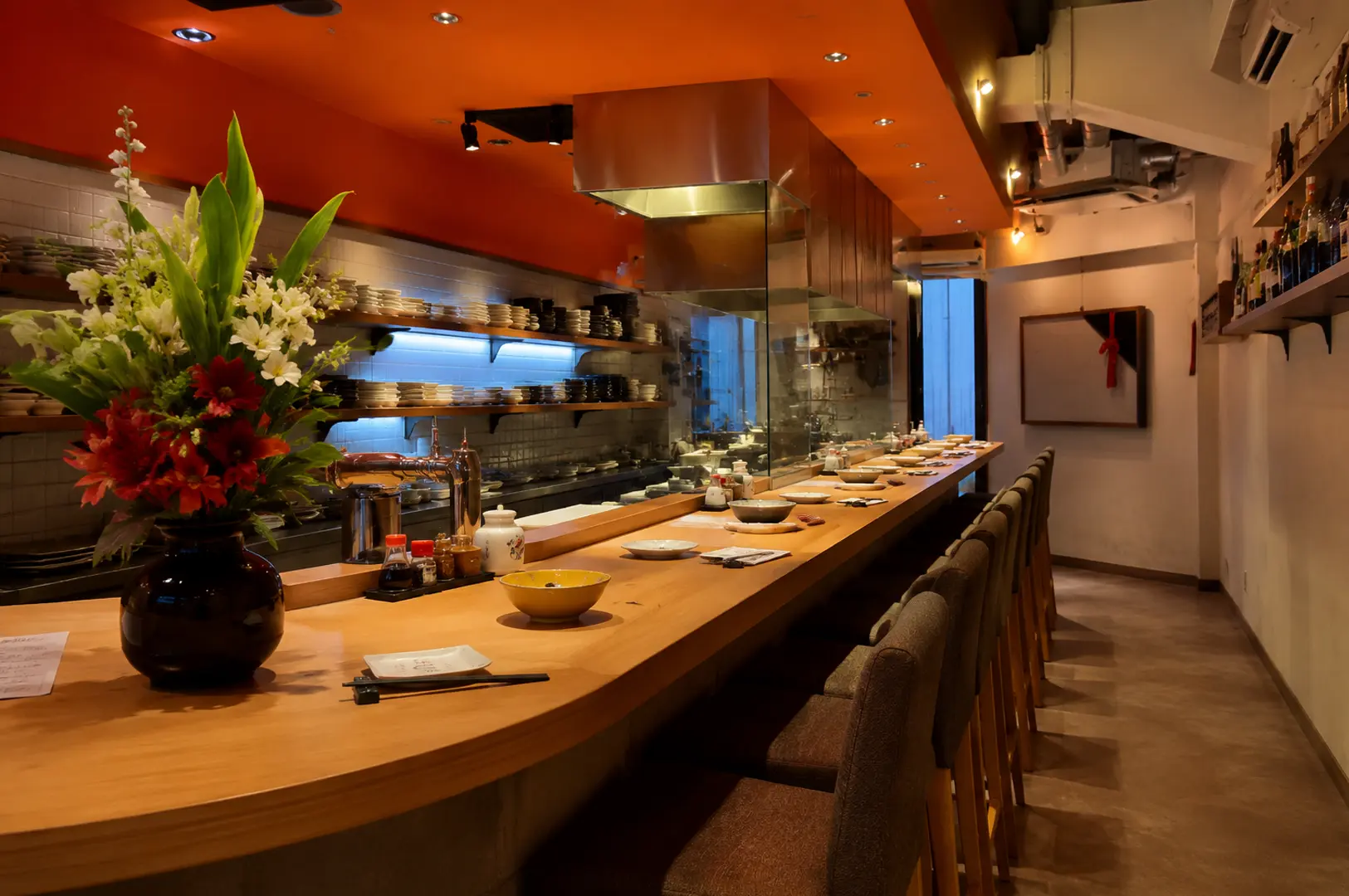 Warm and elegant Japanese sushi bar interior with wooden counter seating and an open kitchen.
