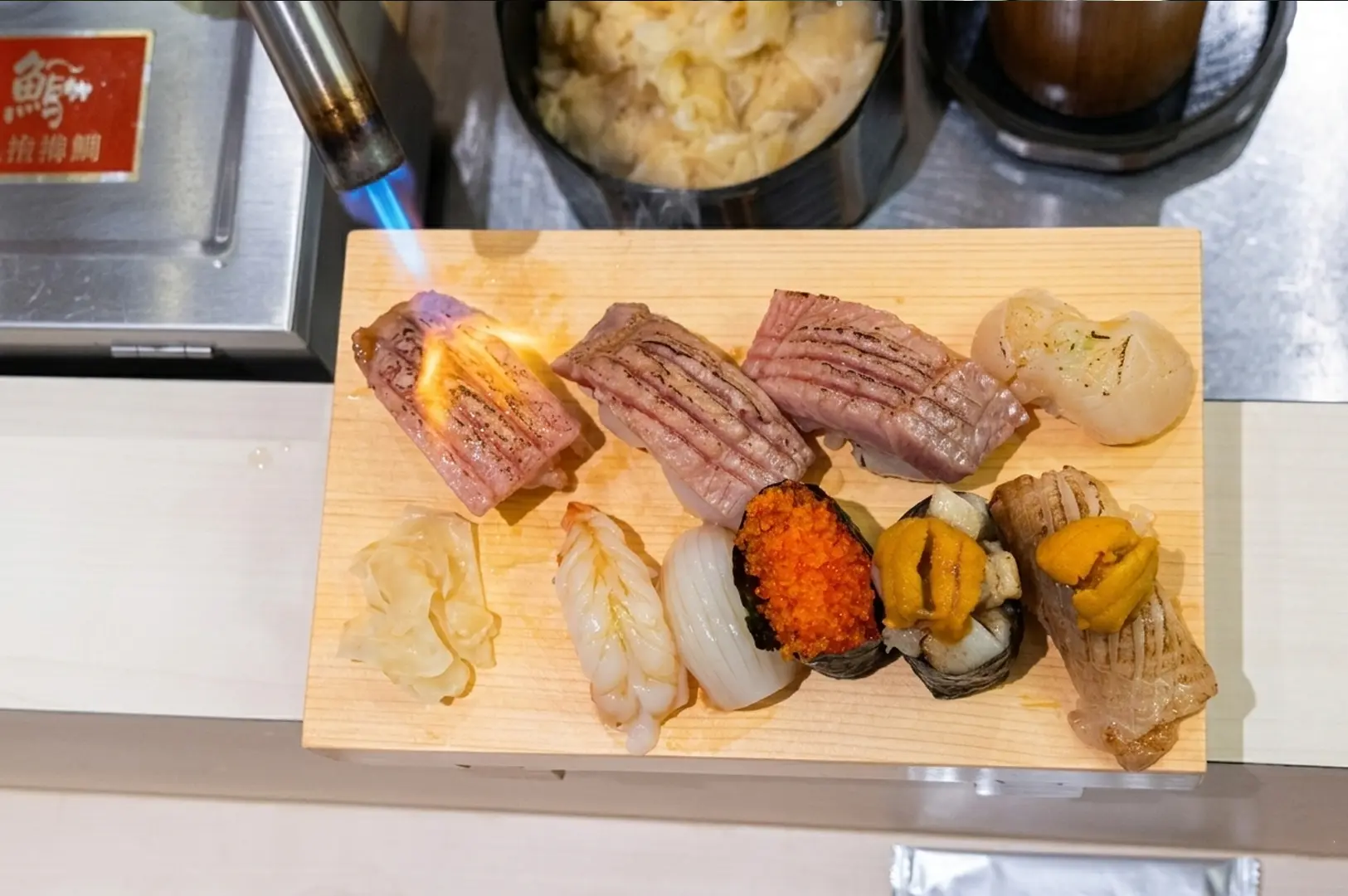 Assorted sushi platter at Junryo featuring torched beef and fresh nigiri being seared with a blowtorch