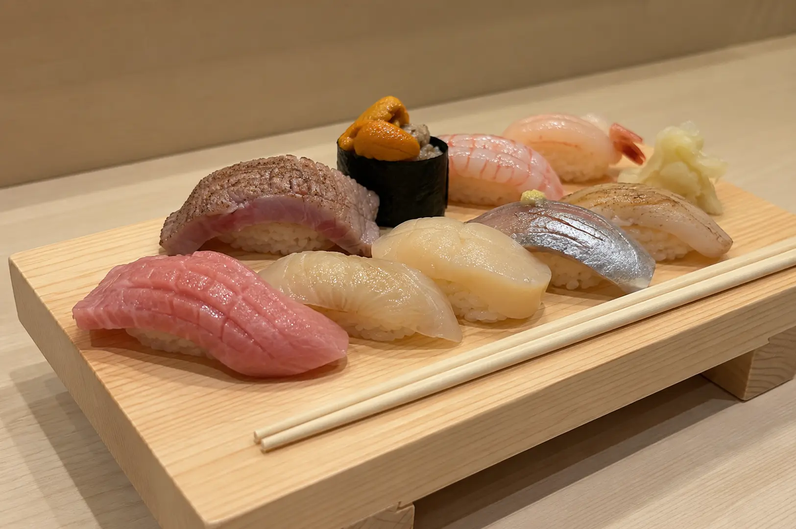Assorted premium sushi served on a wooden board with fresh uni, tuna, white fish, and shrimp nigiri at a Japanese sushi counter.