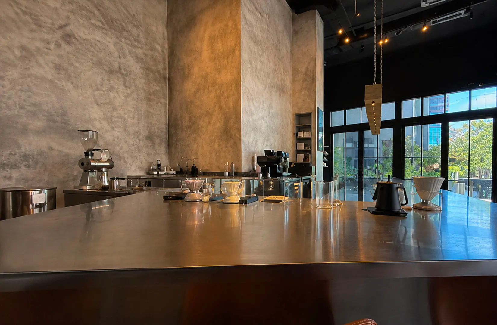 Modern minimalist coffee bar with pour-over brewing station and tall industrial interior.
