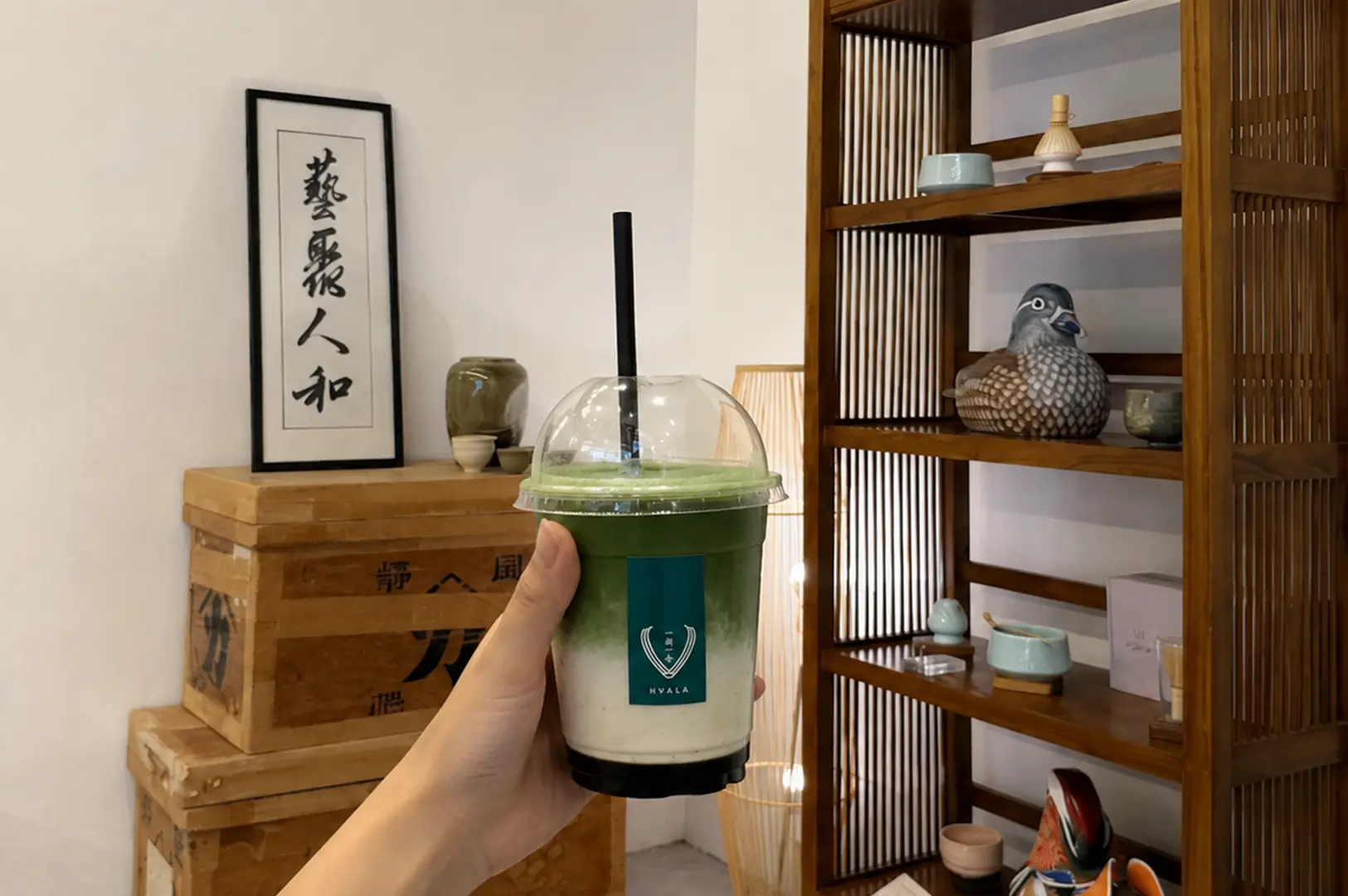 Hand holding a Hvala matcha drink in a minimalist setting