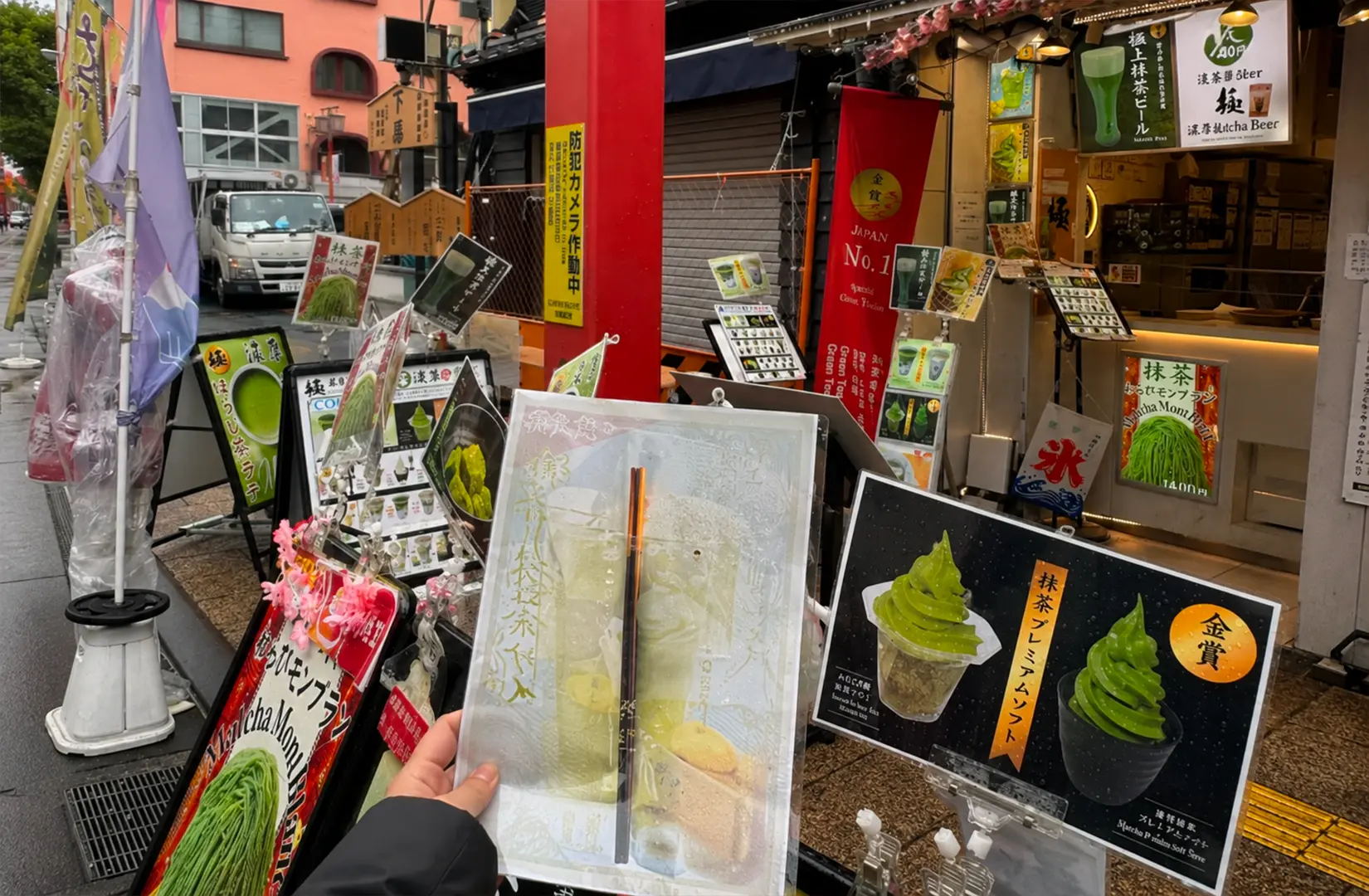 Street stall in Japan displaying matcha soft serve and drinks with a customer holding a menu