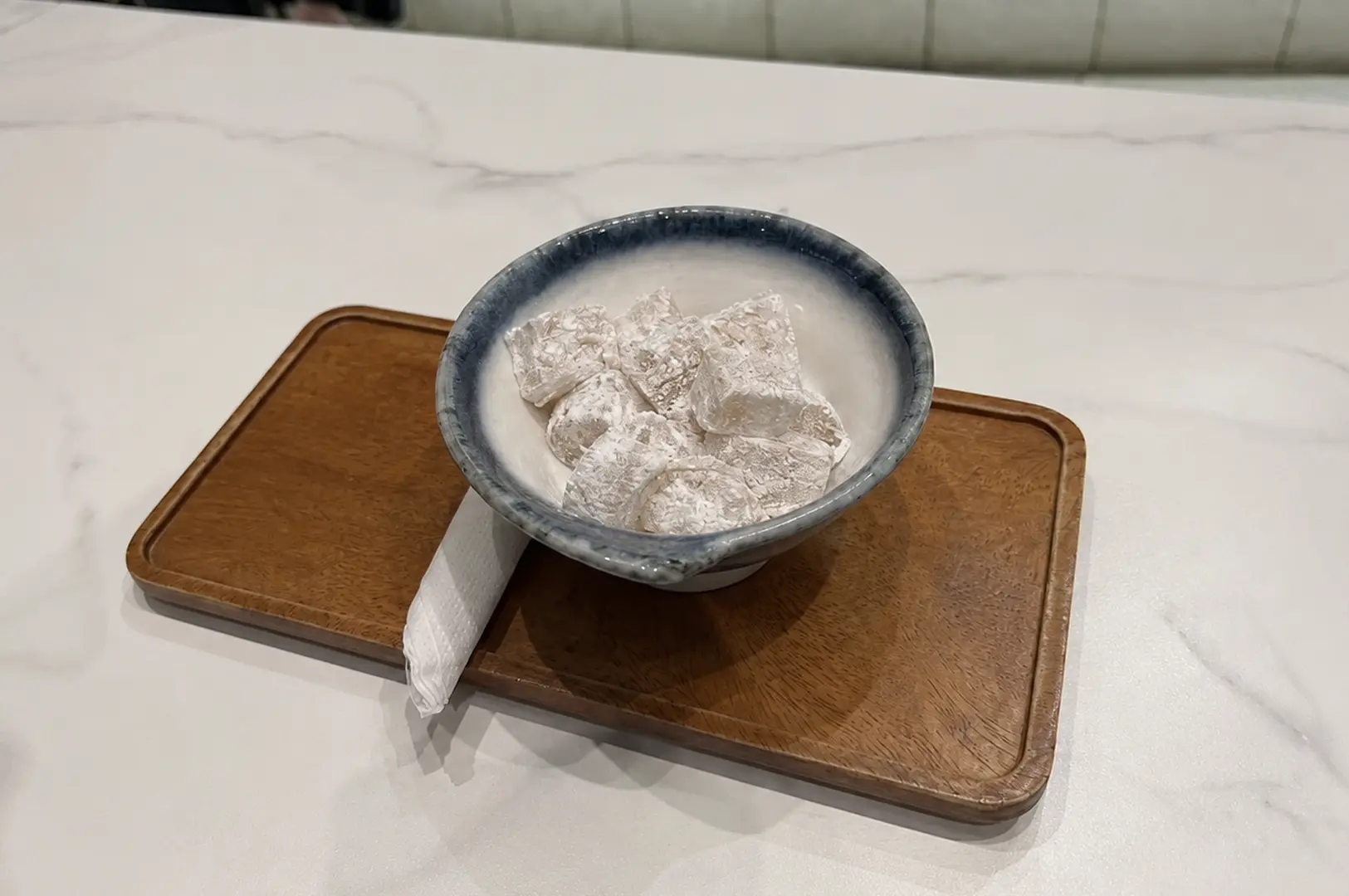 Bowl of powdered Japanese sweets Yuzu Warabi Mochi on a wooden tray