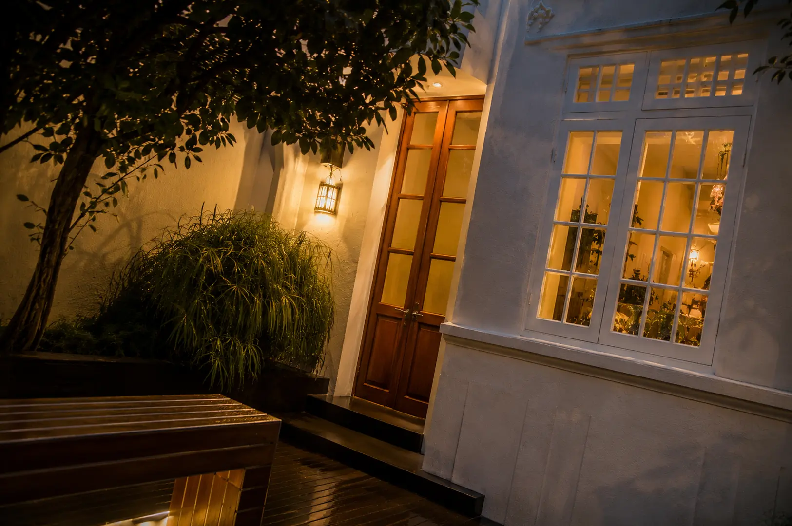 Nighttime exterior of Zén restaurant at Bukit Pasoh Road, featuring a white colonial facade, warm glowing windows, and a wooden entrance door