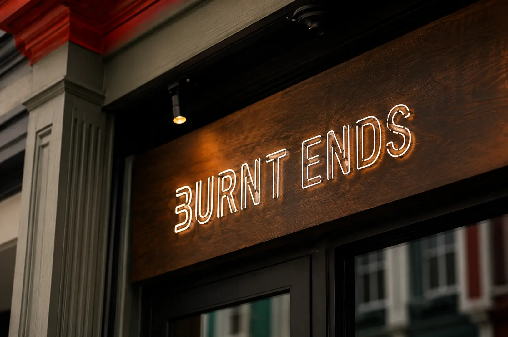 Illuminated "Burnt Ends" neon sign mounted on a dark wooden panel above the restaurant entrance