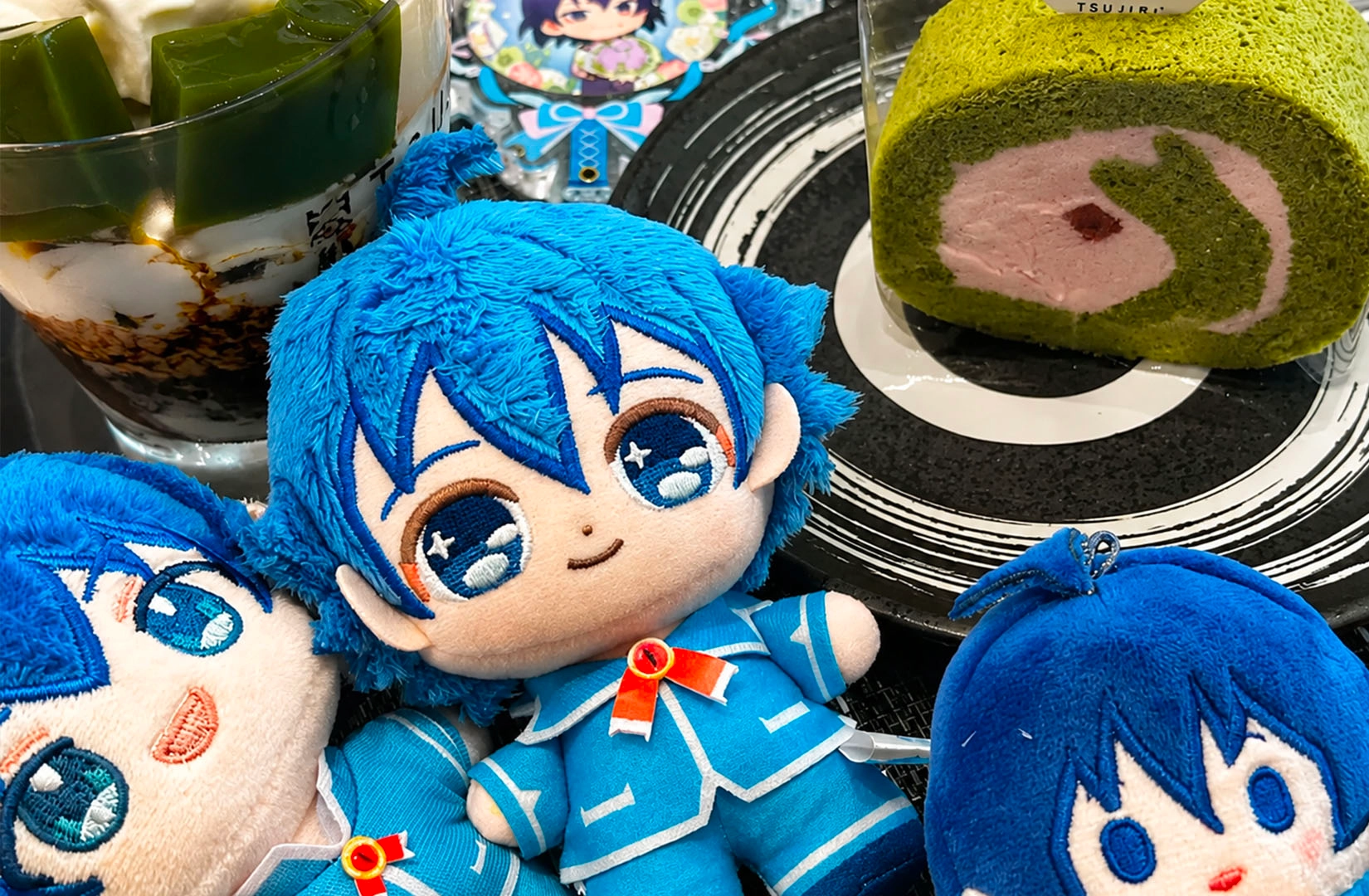 Blue anime plush with matcha desserts and Swiss roll