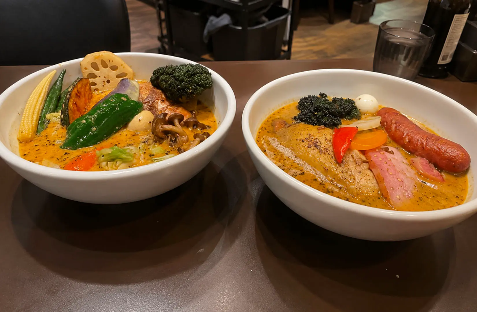 Two bowls of Hokkaido soup curry topped with vegetables and meat