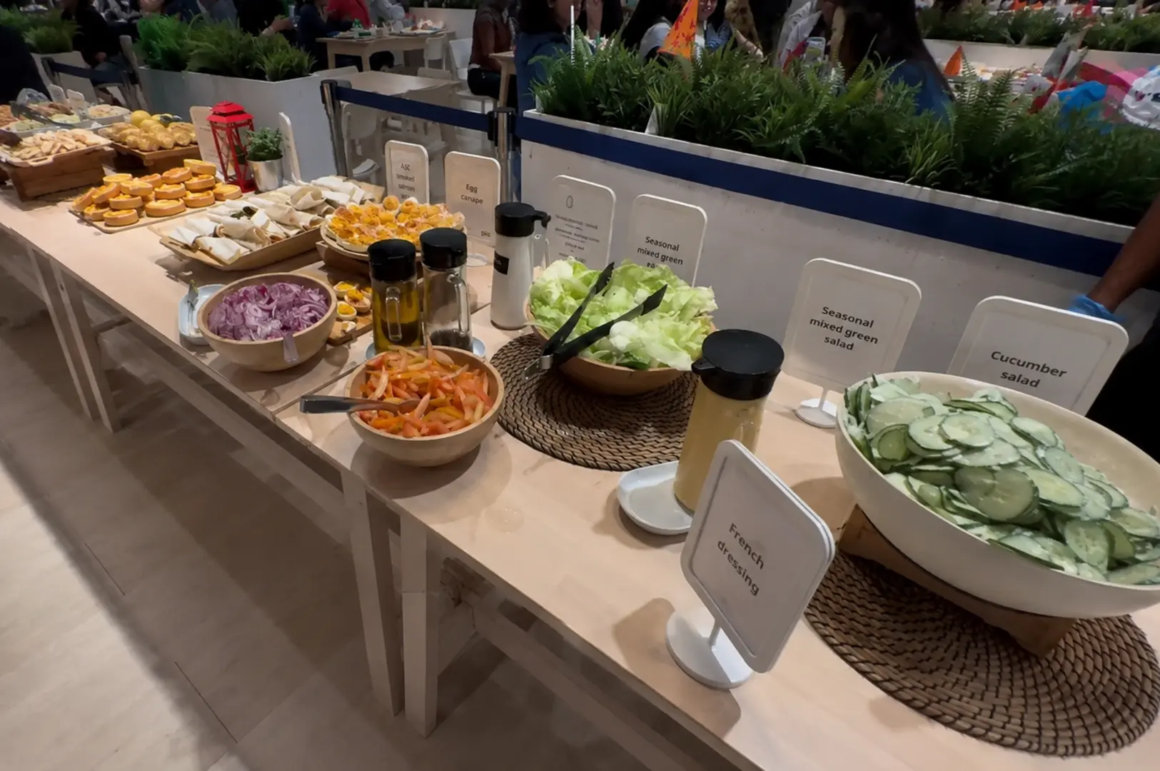 Long IKEA buffet table filled with salads, wraps, eggs, and dressings.
