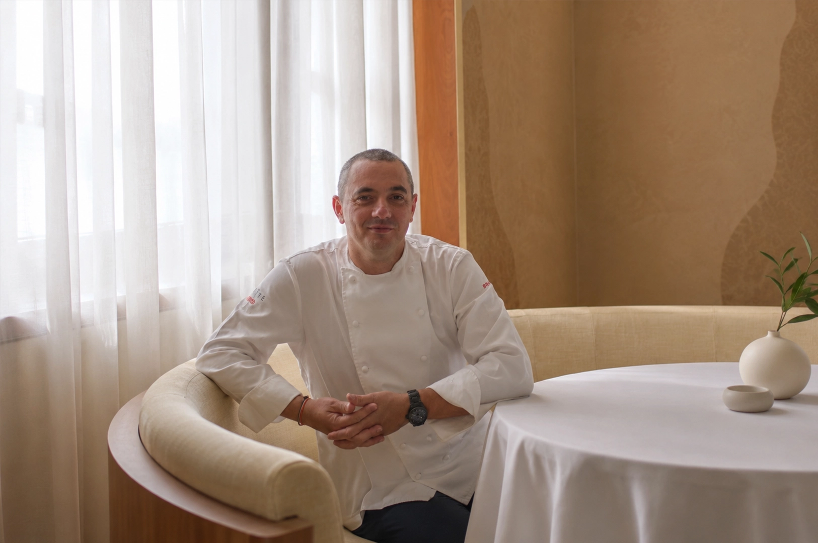 Head chef seated inside Odette Singapore's refined dining room, highlighting the restaurant's warm and intimate fine dining atmosphere.