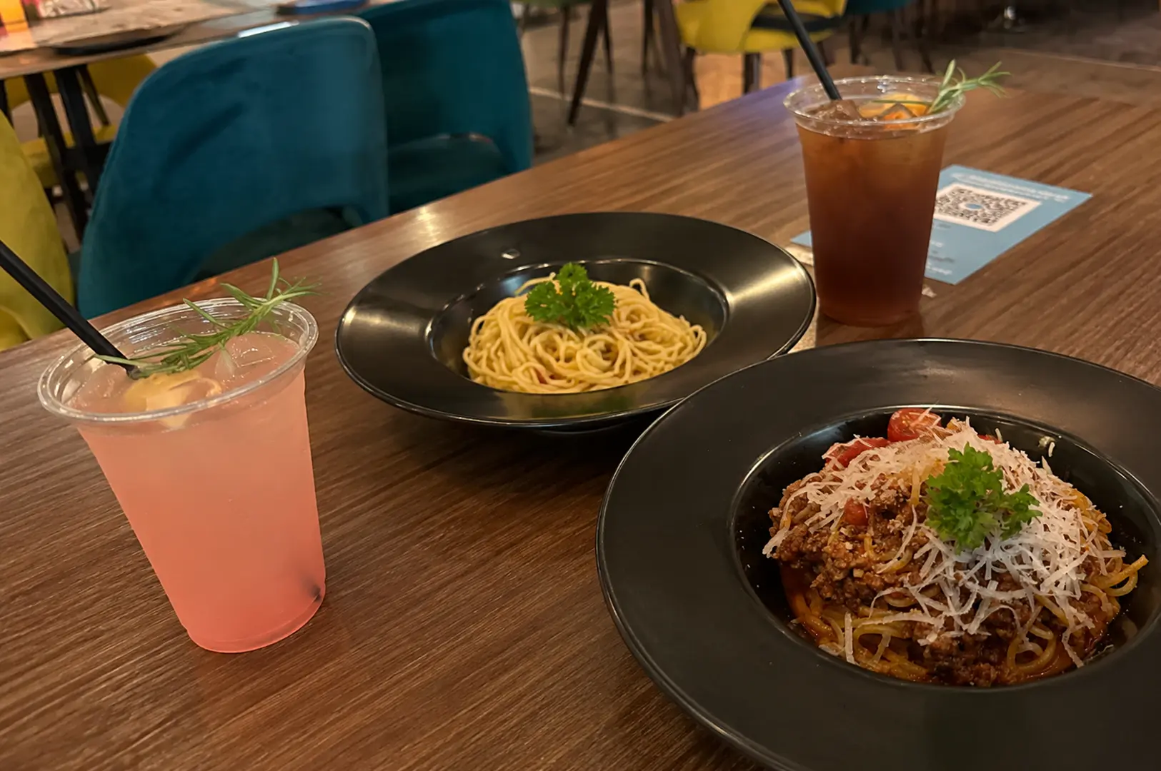 Pasta dishes and refreshing drinks served on a wooden table at Hangar66 Cafe.