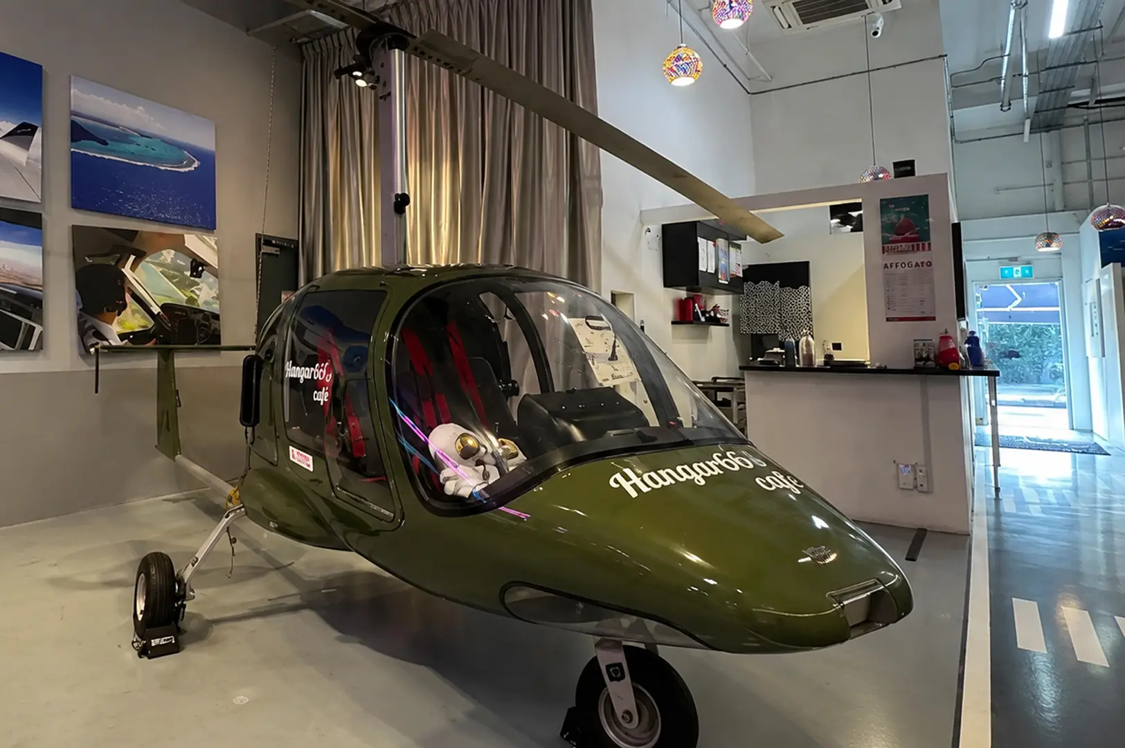 Small helicopter displayed inside Hangar66 Cafe with aviation-inspired interior design.