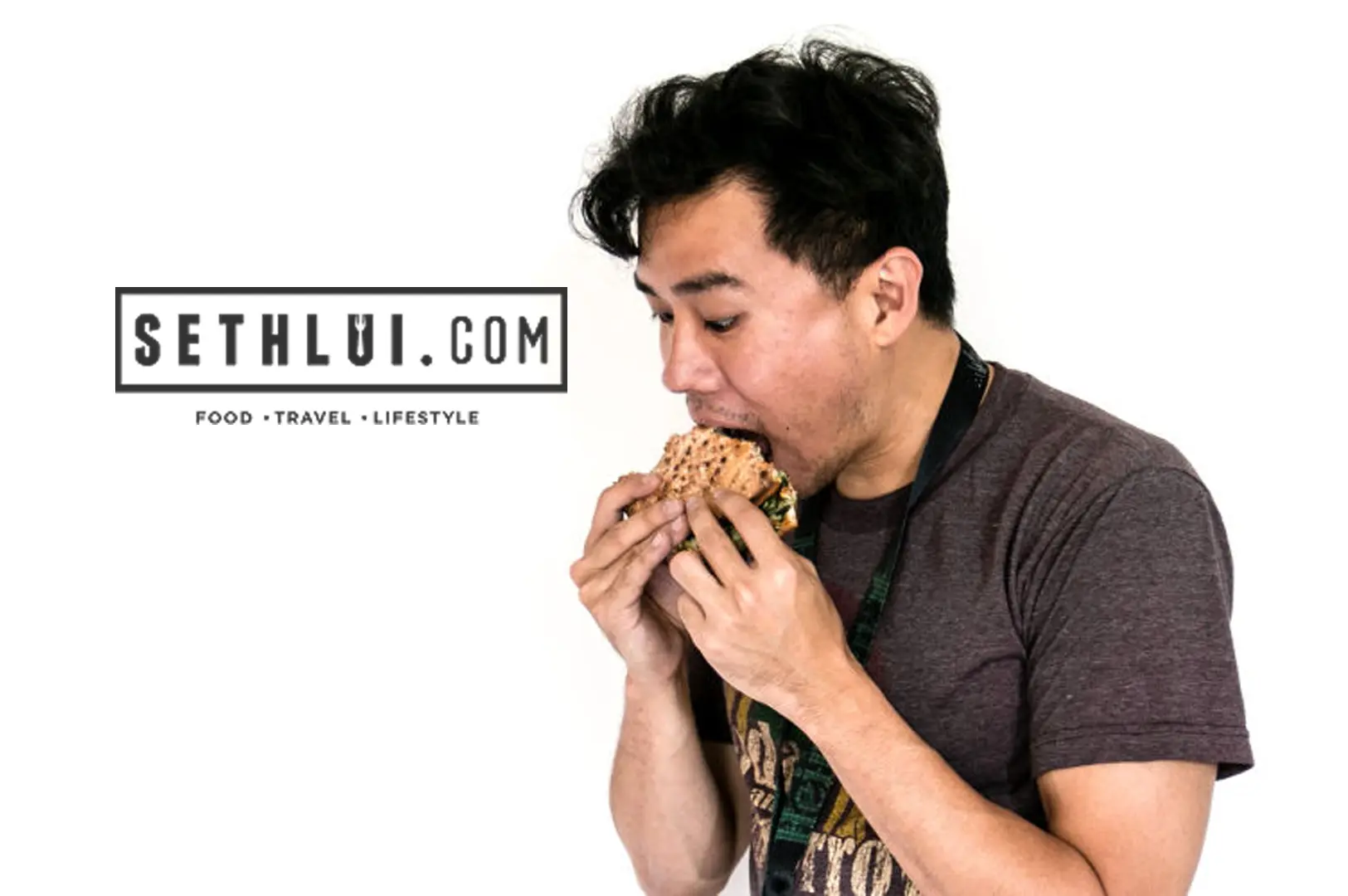 Seth Lui enthusiastically taking a huge bite out of a sandwich next to his food and travel blog logo