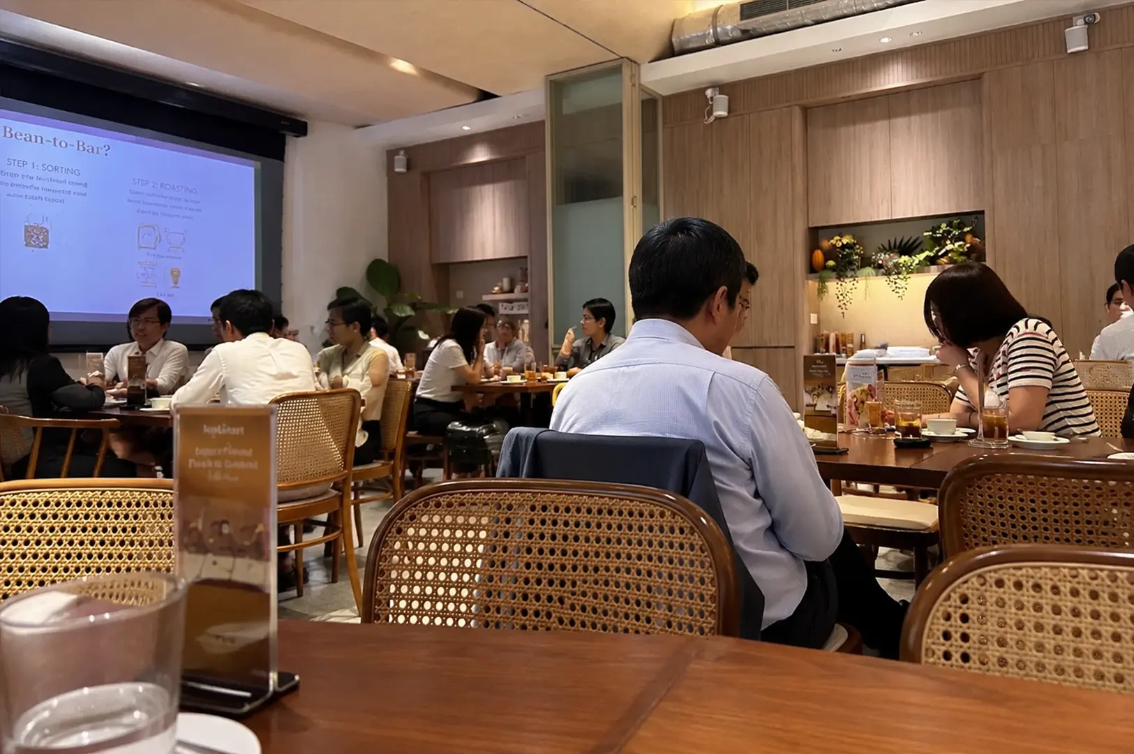 Customer's view inside Mr. Bucket Chocolaterie featuring warm wooden interiors, relaxed seating, and guests enjoying a quiet afternoon gathering.