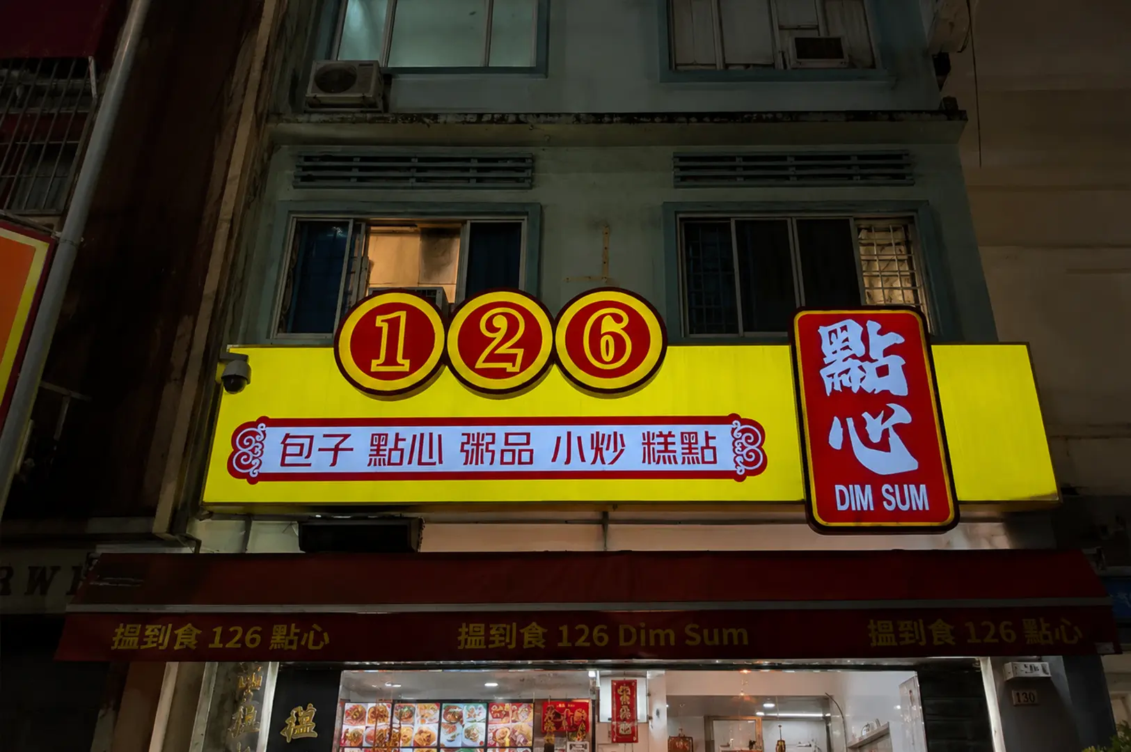 Bright yellow 126 Dim Sum restaurant sign on a nighttime street with Chinese and English lettering.