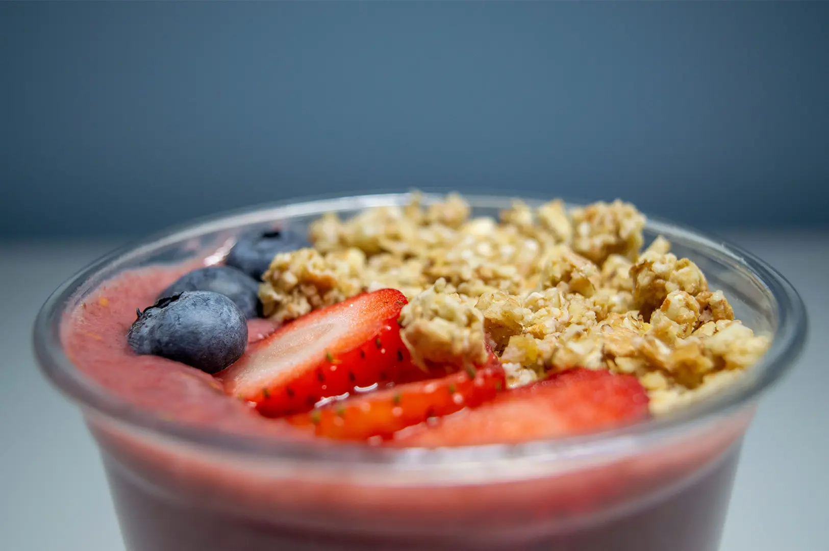 Berry smoothie bowl topped with granola, strawberries, and blueberries.