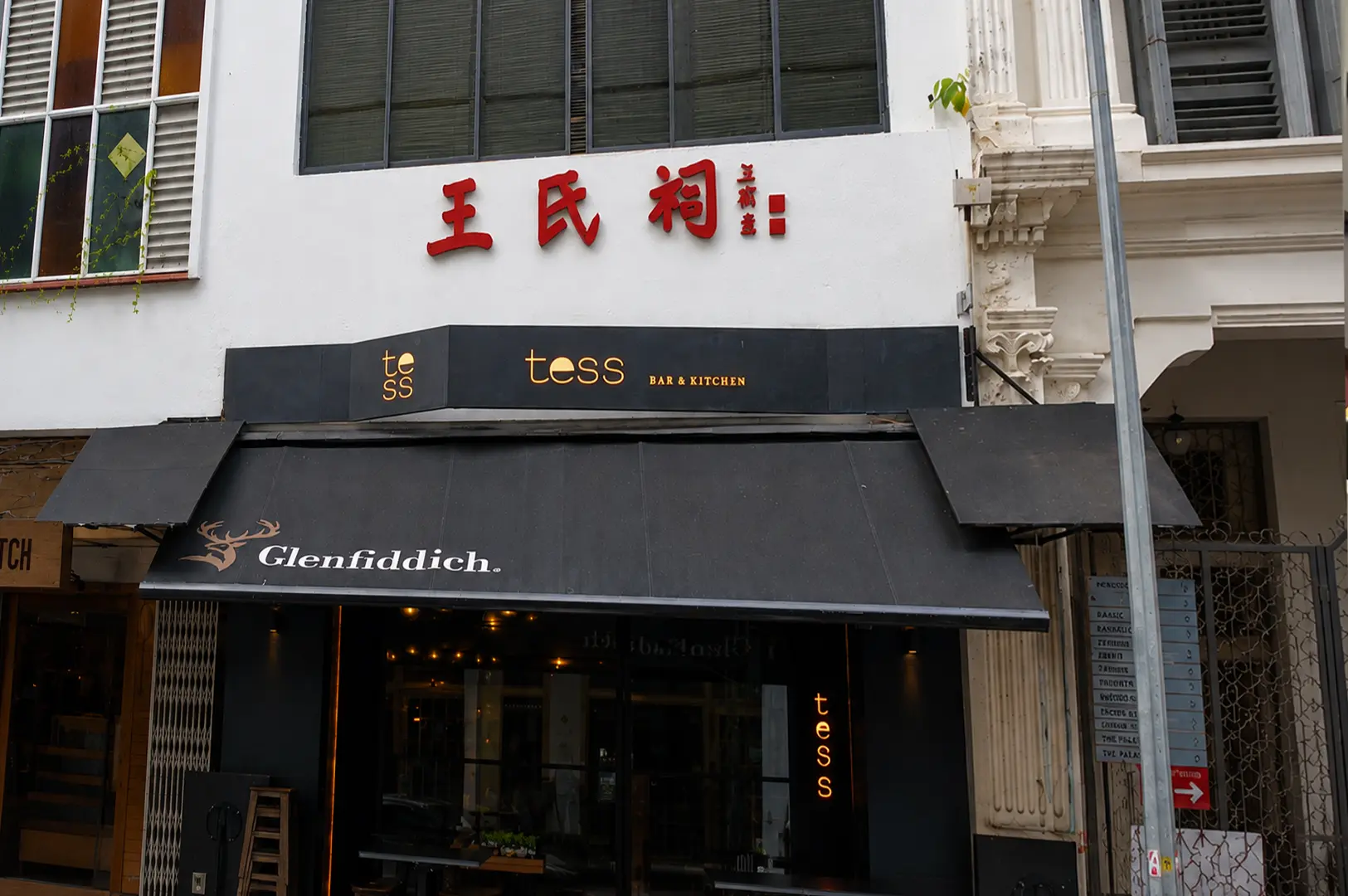 Exterior of Tess Bar & Kitchen with its entrance and Chinese signage above the storefront.