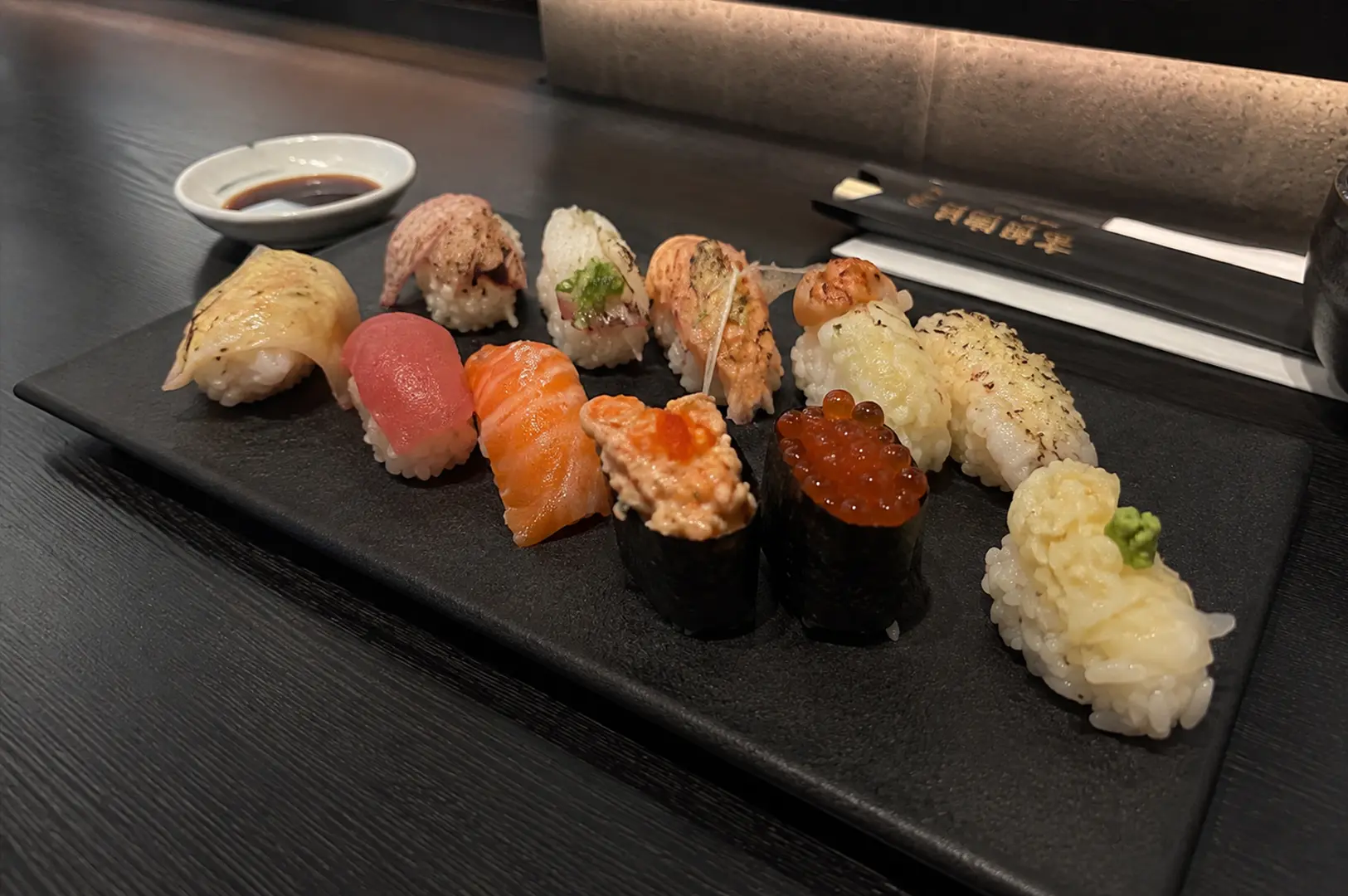 A close-up of assorted nigiri arranged on a dark plate, including tuna, salmon, seared fish, roe, and other specialty sushi at Sen-ryo.