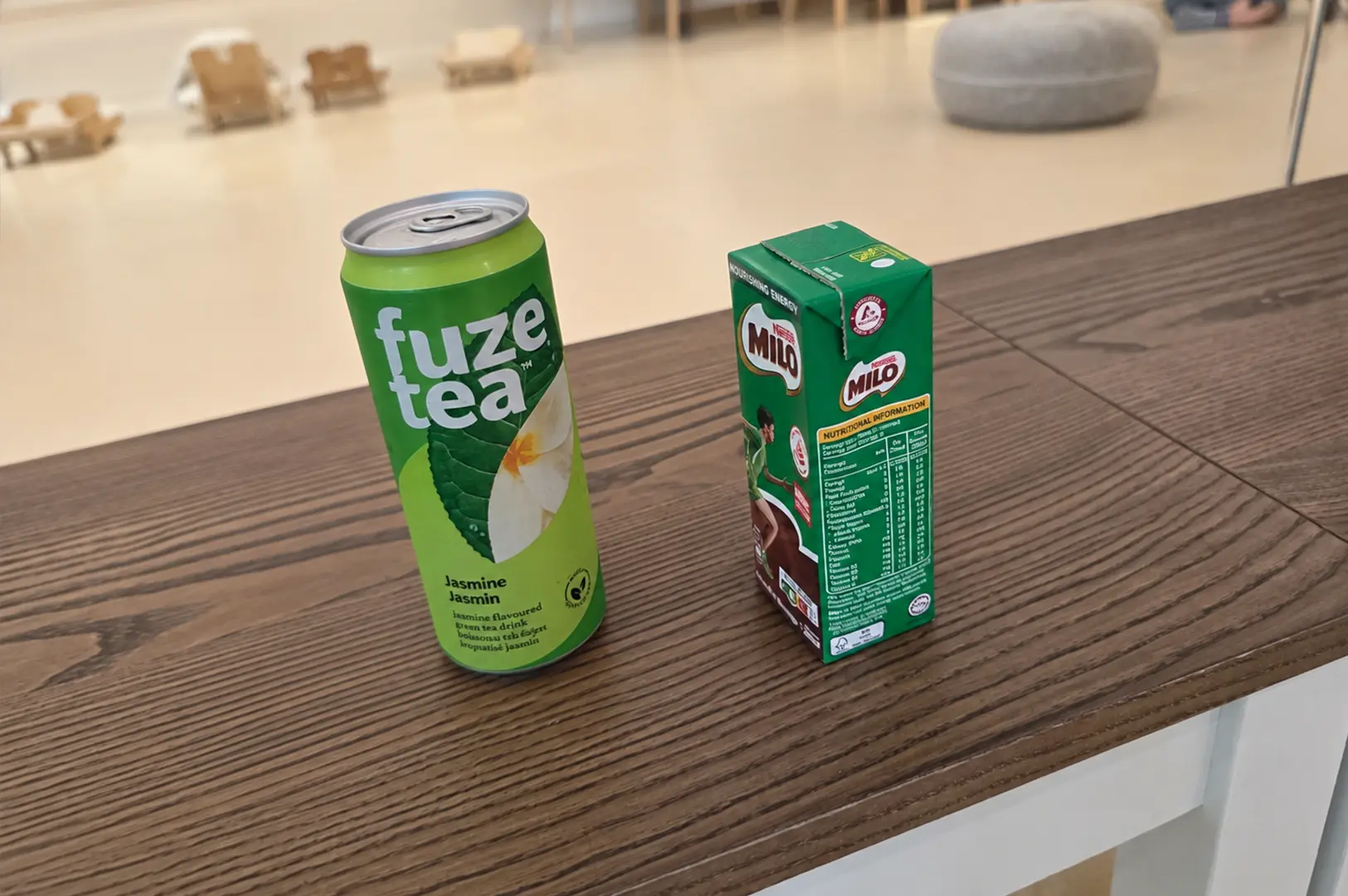 Complimentary drinks including Fuze Tea and Milo placed on a wooden table inside the cat cafe.
