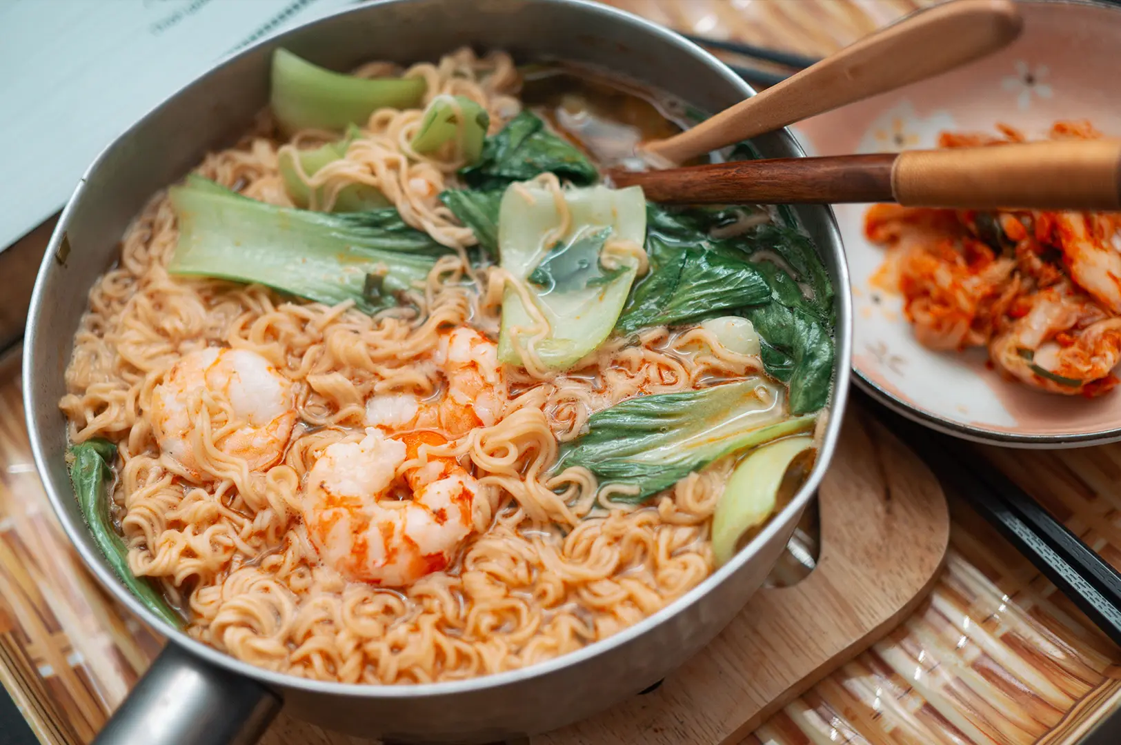 Instant noodle soup topped with prawns, bok choy, and served with kimchi.
