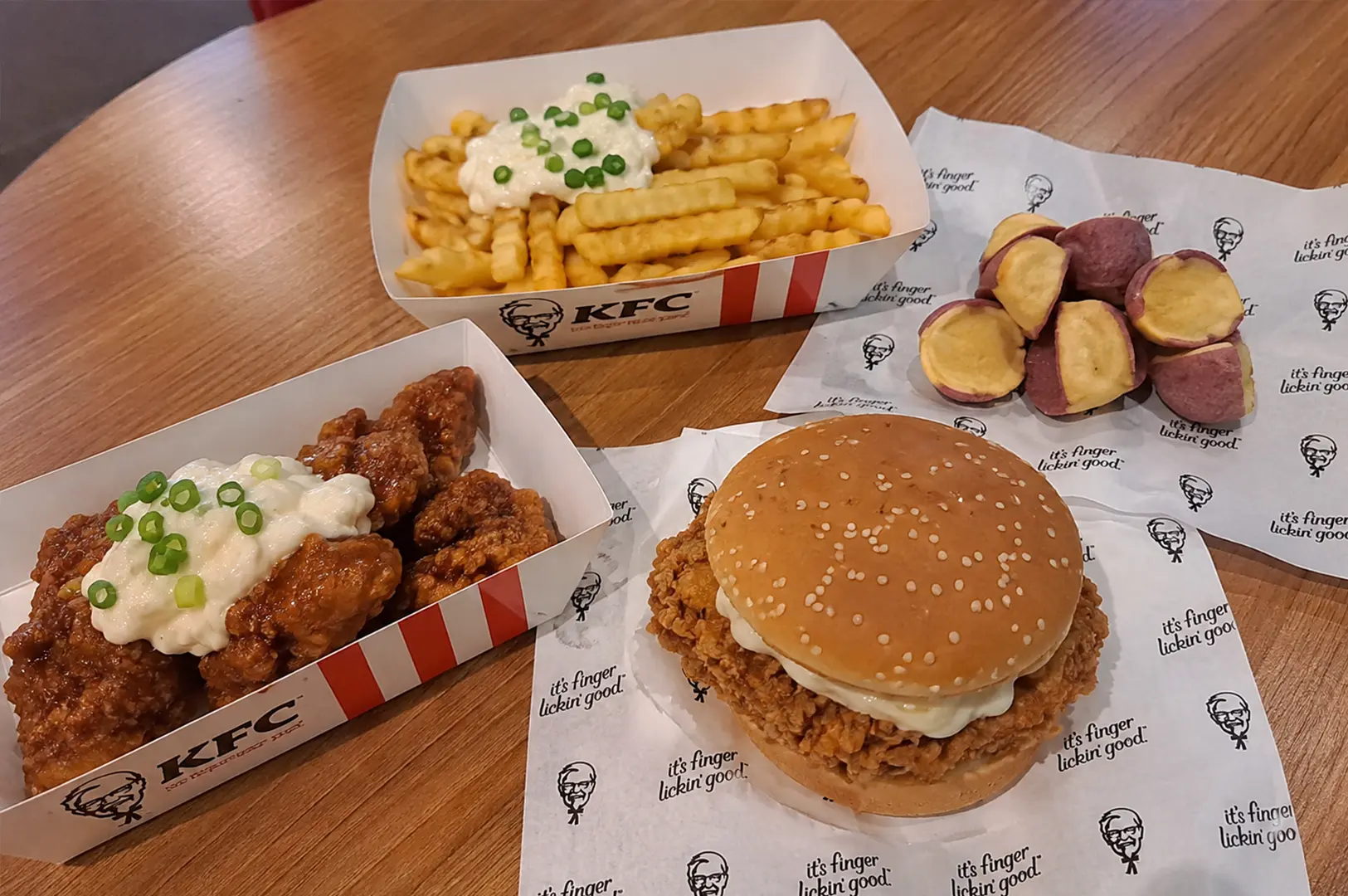 KFC Singapore Pokémon collaboration featuring Japanese Nanban Zinger and bites, served with loaded fries and purple sweet potato sides on a table.