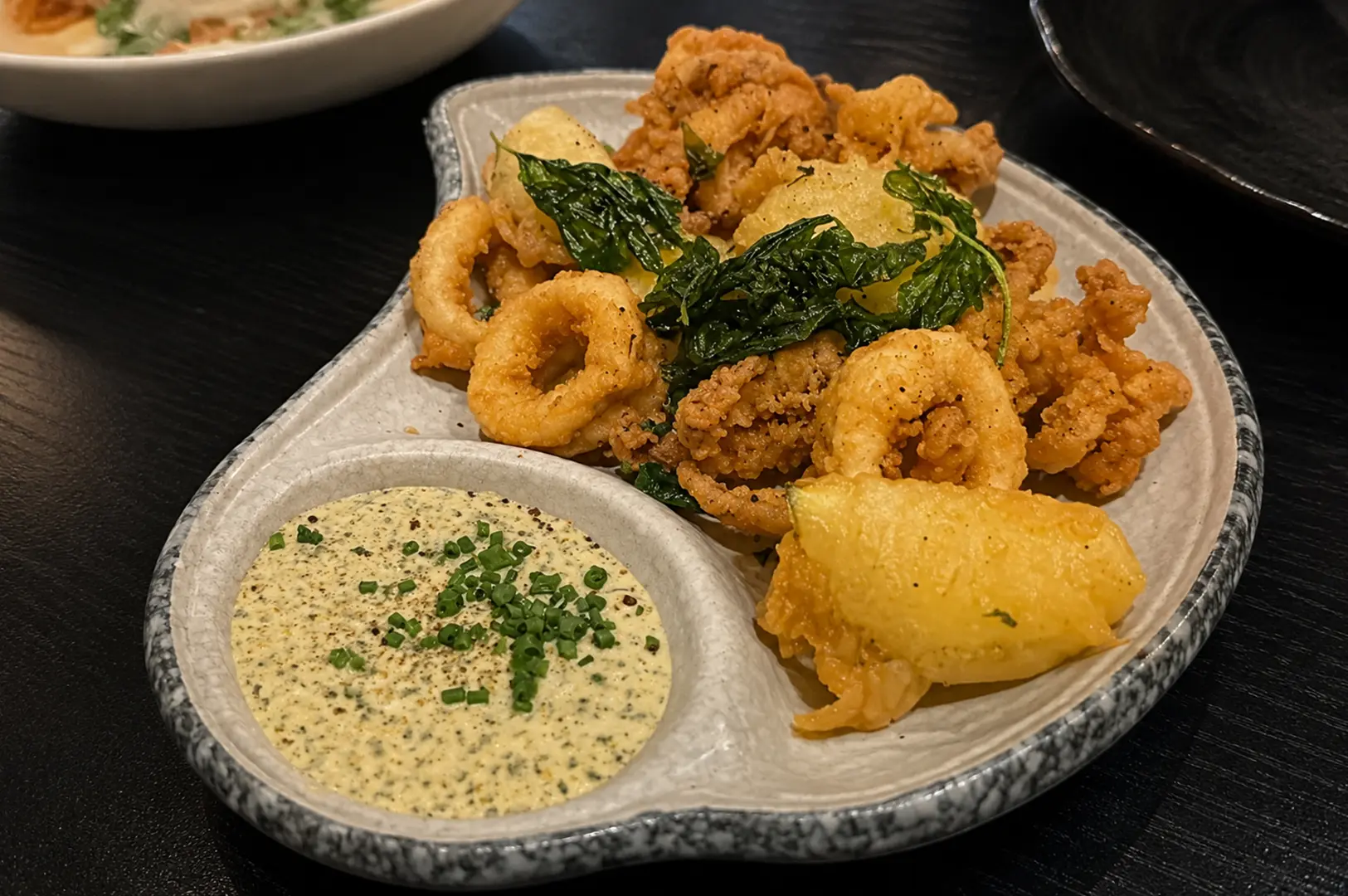 Deep Fried Calamari with Smoked Aioli, crispy basil, and lemon wedges.