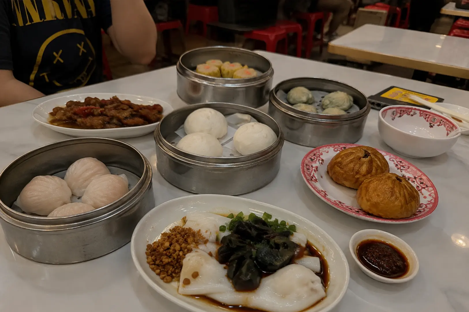 Table filled with steamed dim sum, buns, rice rolls, and pastries at 126 Dim Sum.