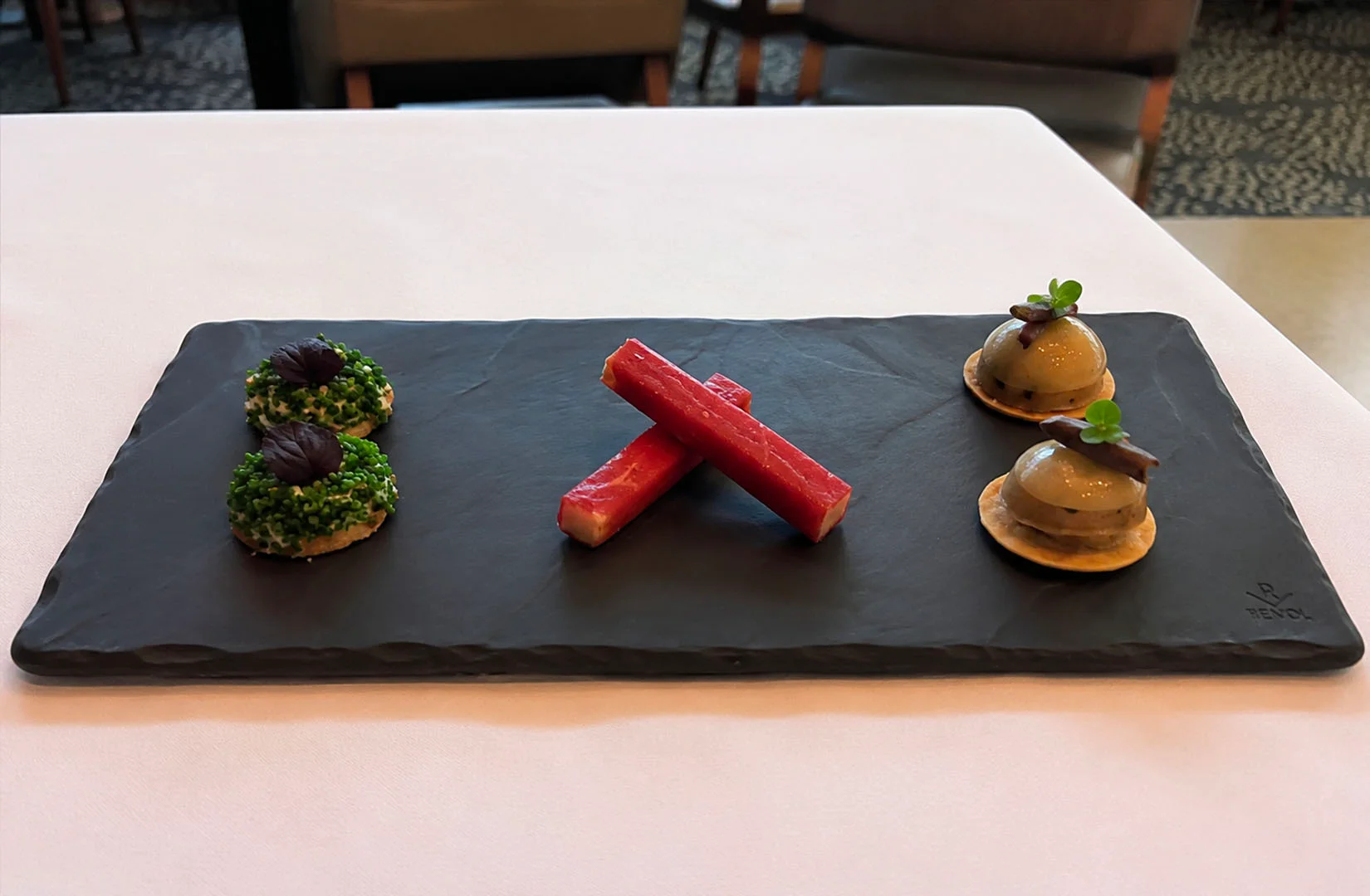 Elegant assortment of amuse-bouches served on a black slate platter at Les Amis.
