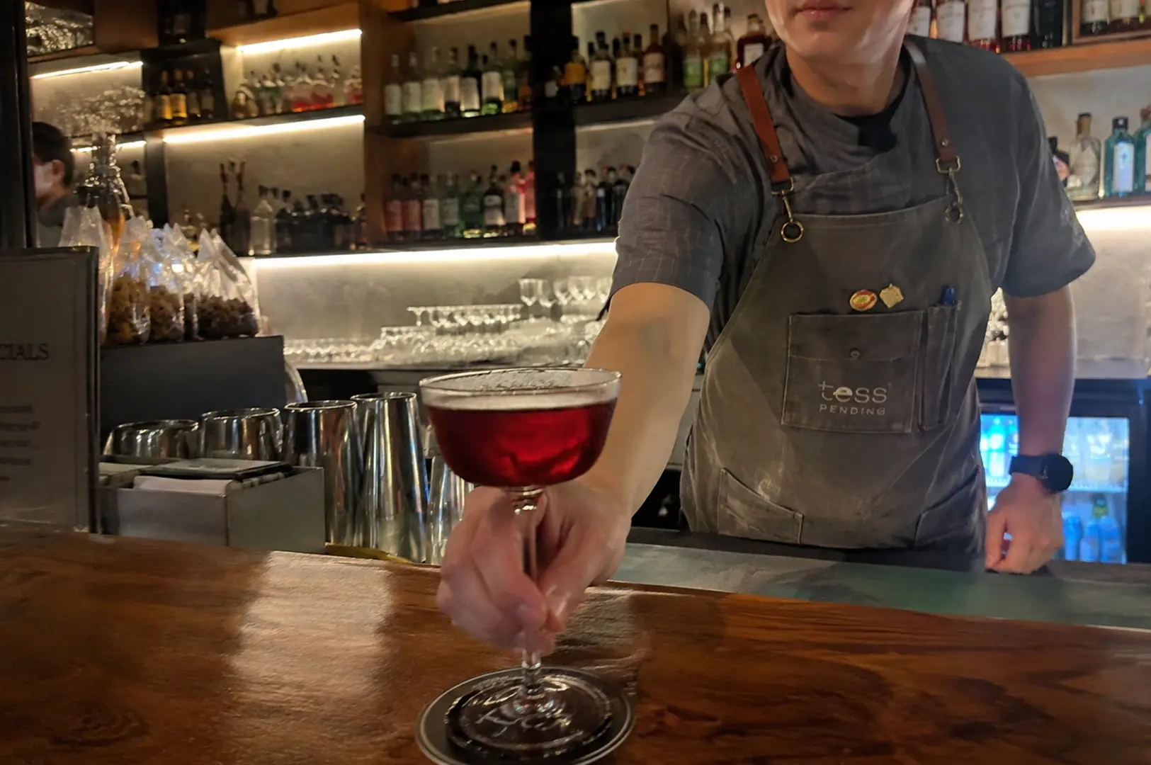 Bartender serving a red cocktail at the bar inside Tess Bar & Kitchen.